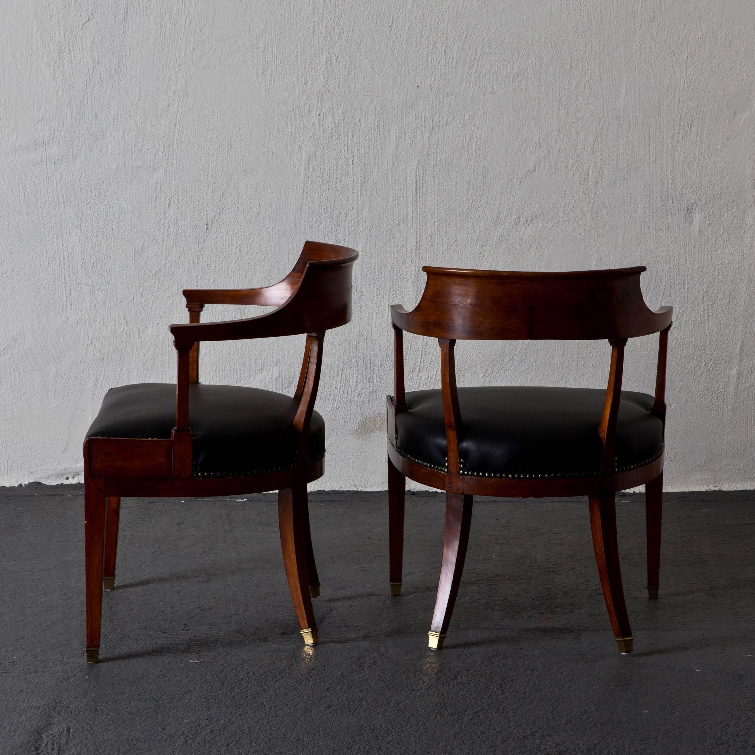 Armchairs desk pair Swedish Karl Johan Sweden. A pair of armchairs made as desk chairs from the Karl Johan period, early 19th century in Sweden. Frame made from mahogany and seats upholstered in soft black leather. Legs on brass casters without