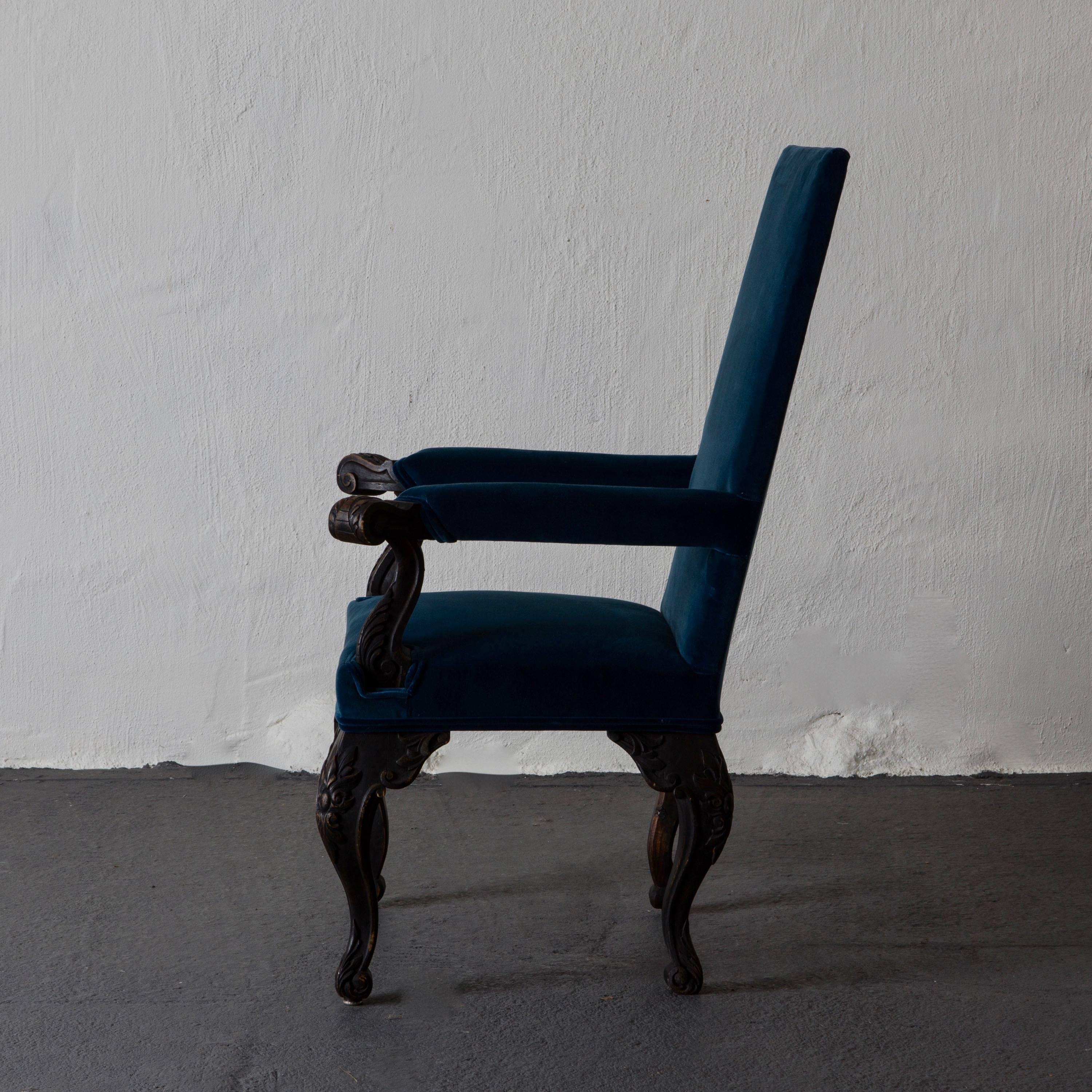 An armchair made during the 19th century in Sweden. Upholstered in a blue with a green hint cotton velvet. Painted in our Laserow black. Leaf carvings on armrests and legs.
 