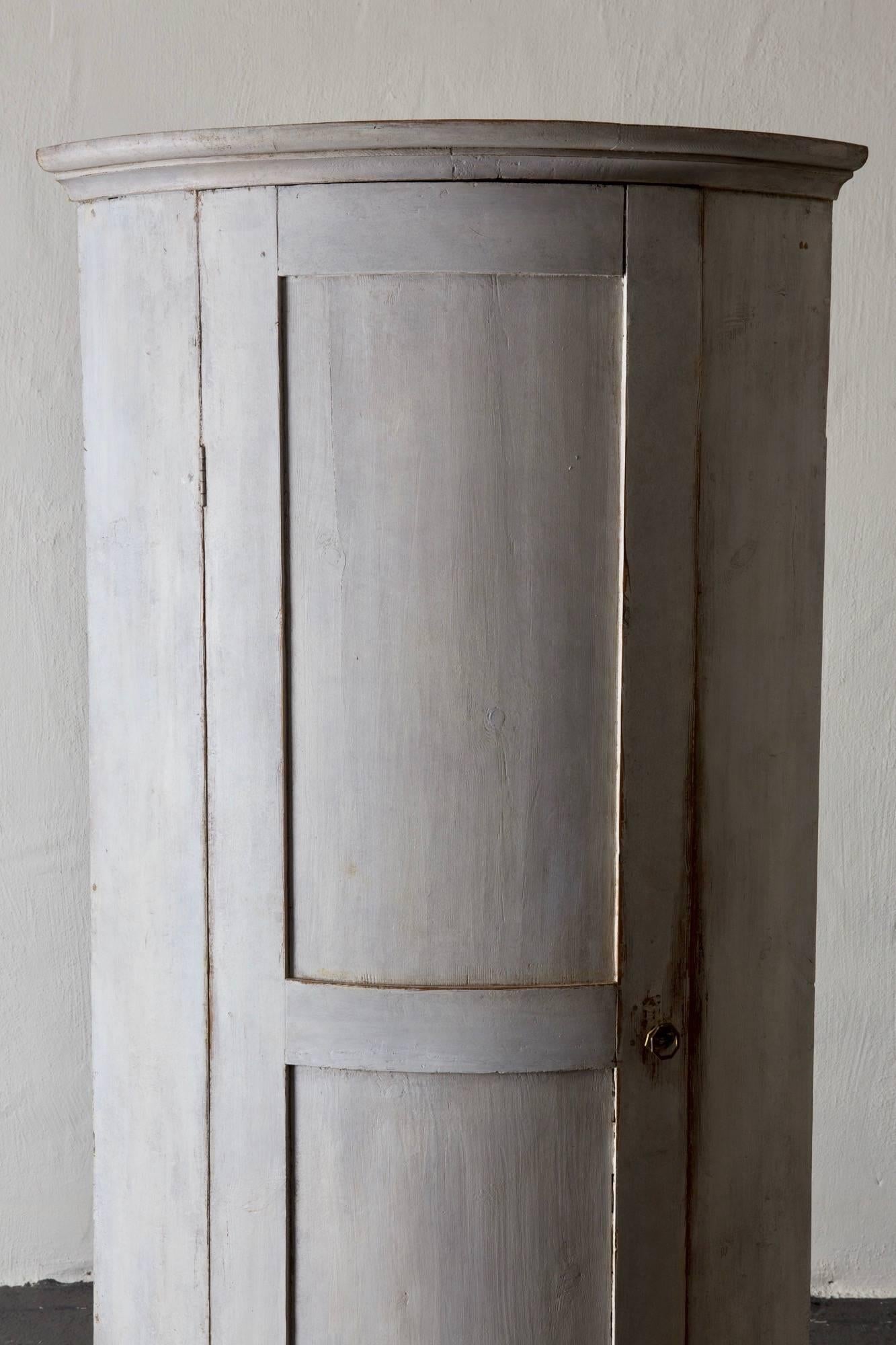 A corner cabinet made during the Gustavian period and early 19th century in Sweden. White distressed finish with a dark gray inside. Both finishes have been restored. Legs have also been restored. 