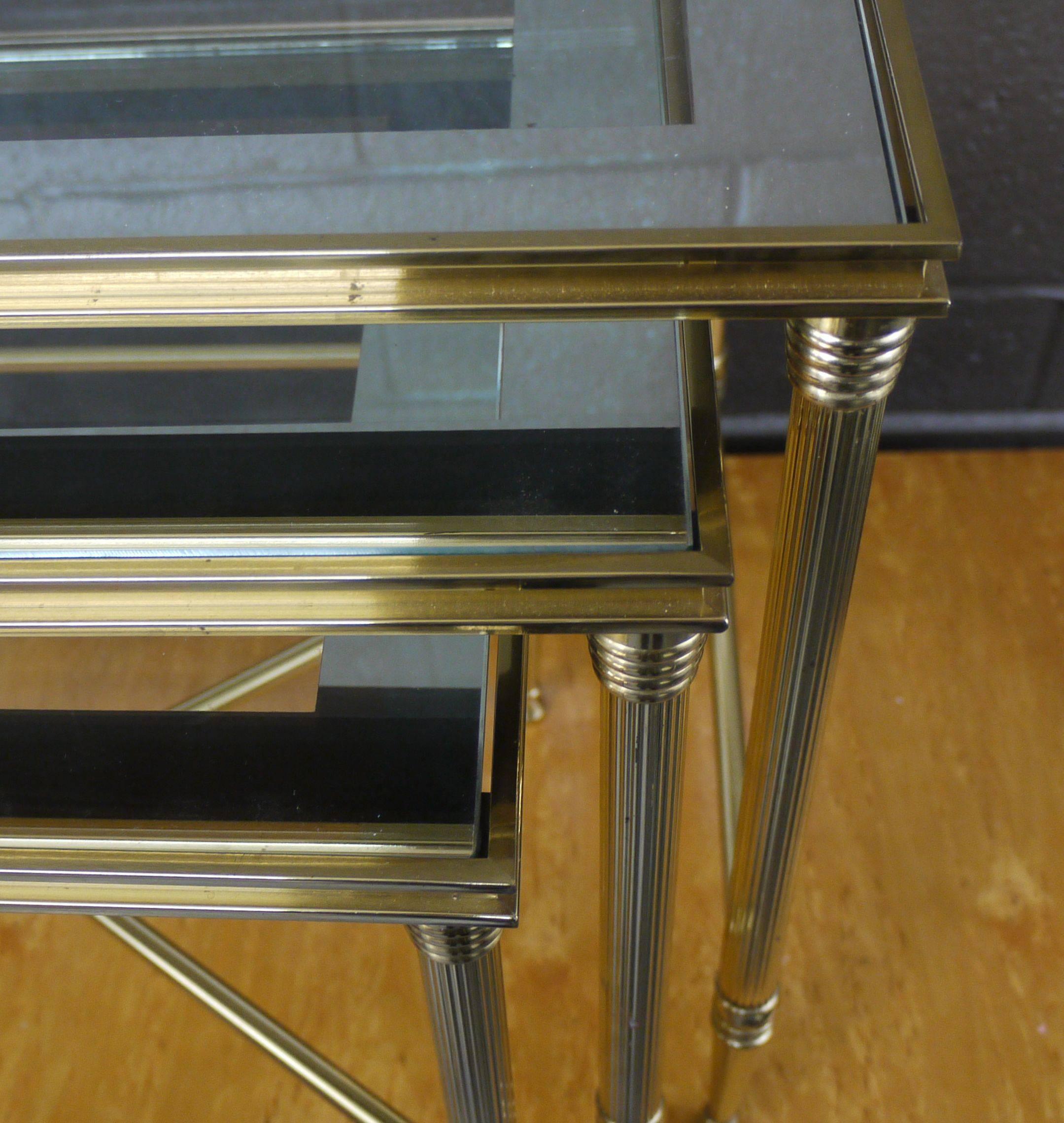 Set of neoclassical polished brass nesting tables, American, circa 1960s. Terrific shape, with original mirrored edge glass.