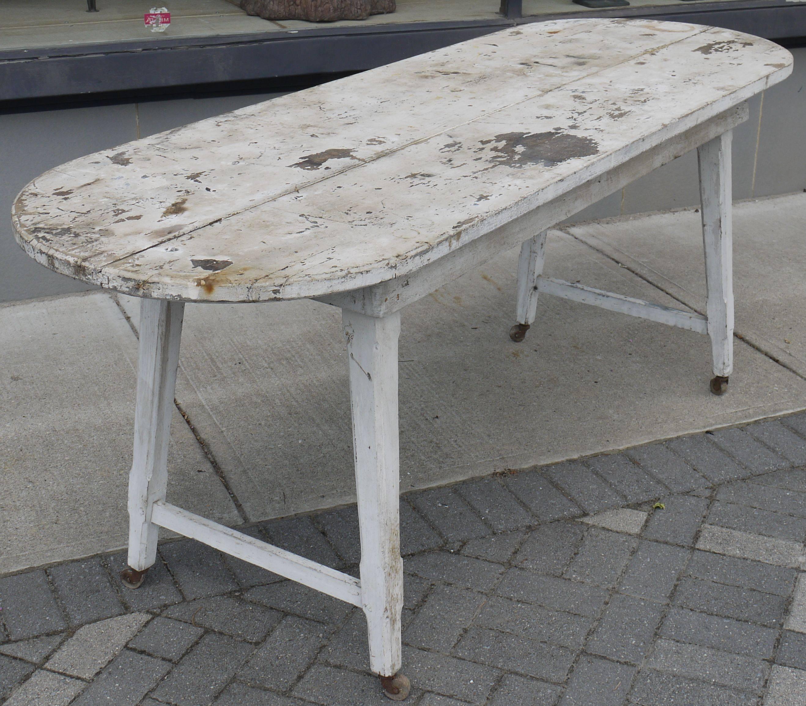 Awesome original paint farm table from a tomato canning factory in Ottoman Virginia which is from near the Chesapeake Bay. Great canted legs racetrack shaped top, peg construction on the bottom part, with original wooden wheels. Be great as a