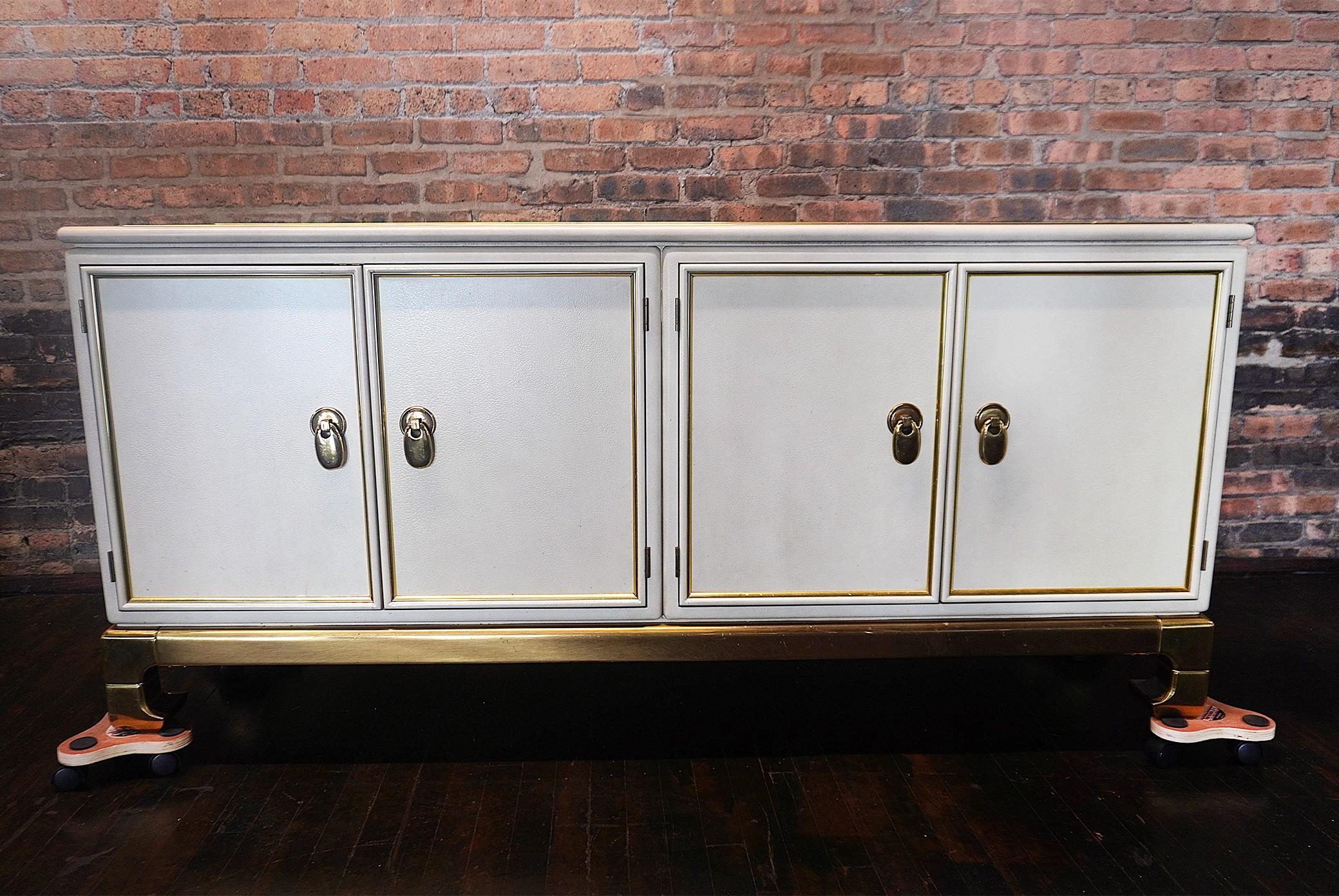 Stunning and rare cream colored faux leather wrapped buffet (sideboard).  There are brass inlays to the top of the buffet and a solid brass base and hardware.  

This piece has a chinoiserie feel.  Made by Mastercraft in Grand Rapids for Richard