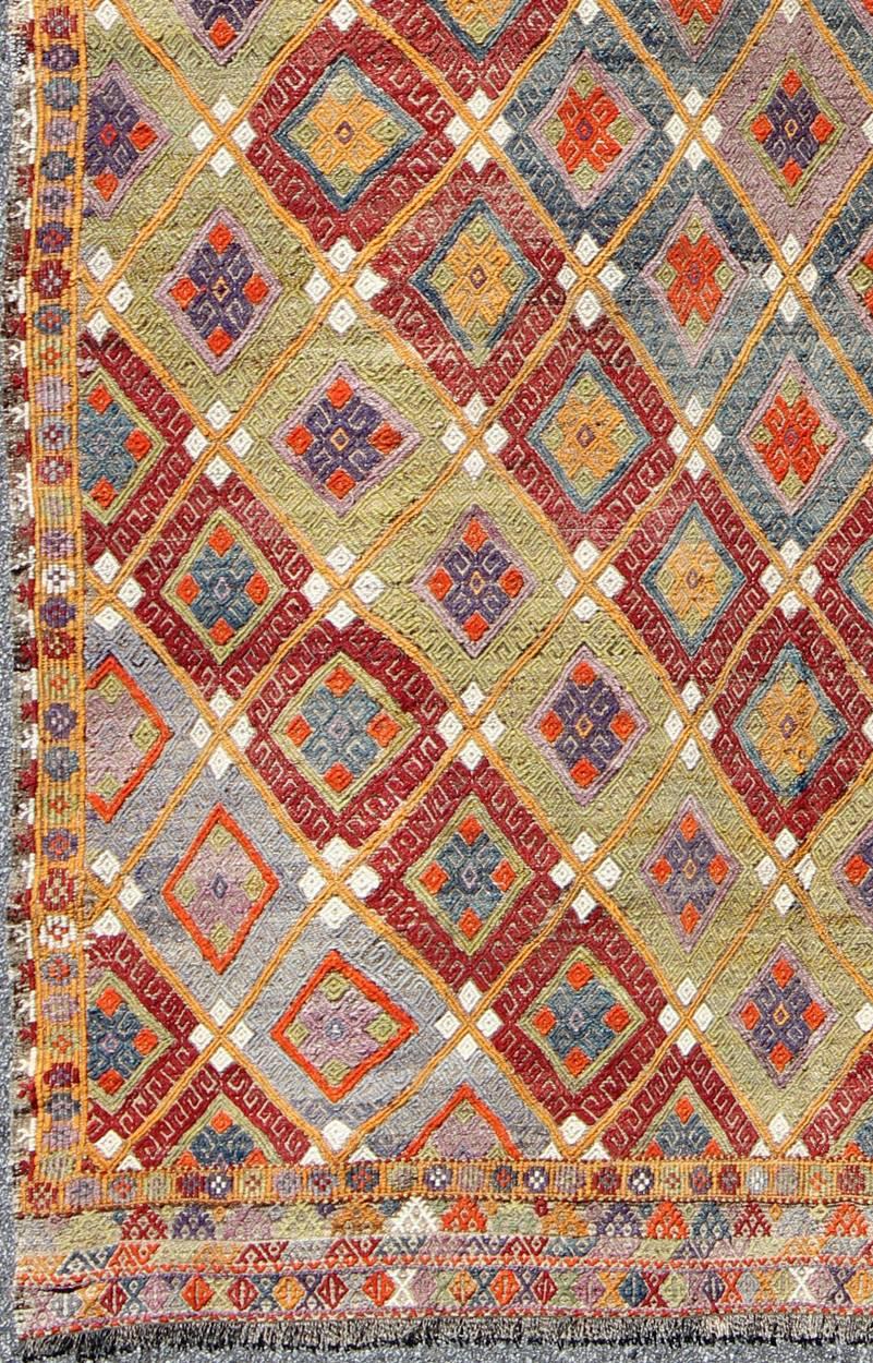 Colorful Kilim/Jijim with Diamonds in Light Green, Light Blue and Red.
Featuring tribal shapes with a spotted and speckled assortment of geometric elements, this unique Mid-Century Jajeem showcases an array of rich colorful tones that have been