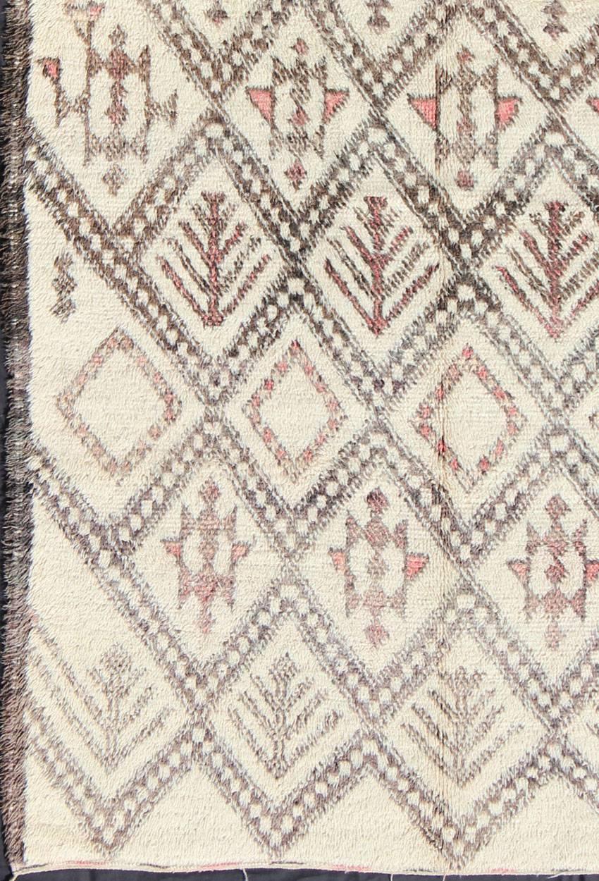 Measures: 6'3 x 11'8.
Woven in light Ivory hand-spun wool with muted salmon, gray and light charcoal symbols, this gorgeous Moroccan rug has a sophisticated lozenge-based grid design that encompasses the entirety of the carpet. The eight-pointed