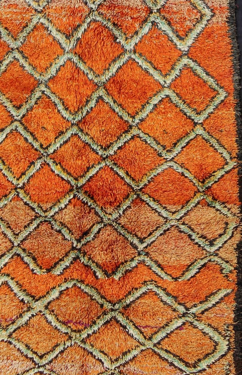 Measures: 4'10'' x 11'4''.
This piece is an extremely lively and colorful vintage Moroccan gallery rug. Featuring lush wool, it was woven in the High Atlas Mountains by the Beni Ourain tribes. The lovely multi-shades of orange plays host to a strong