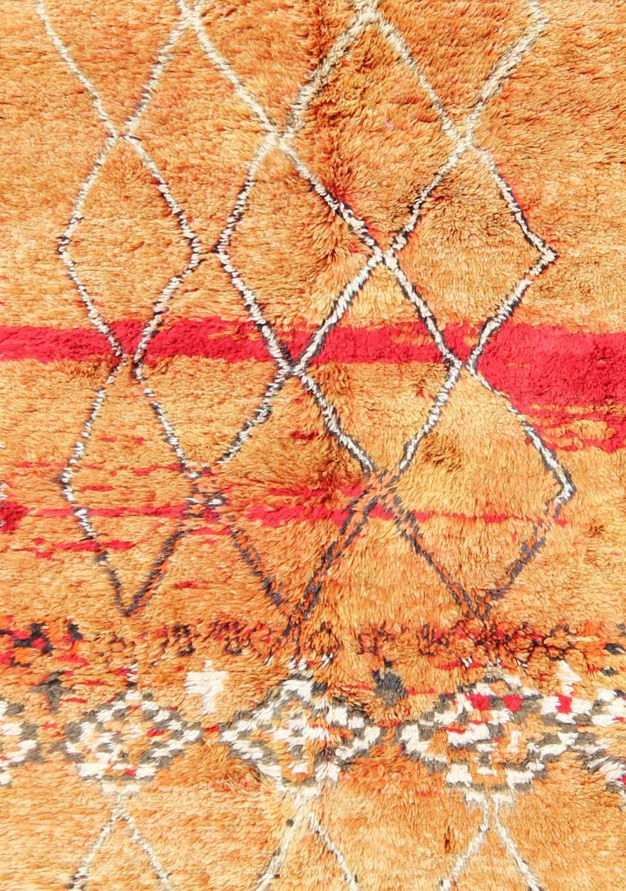 This wonderful vintage Moroccan rug features shades of pale orange, red, and hints of neutral colors. The ivory and black diamond design and geometric shapes create movement while the small checkerboard border enhances the tribal design. 
Measures: