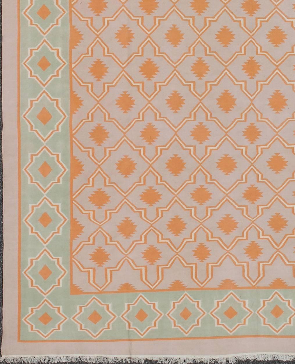 Woven during the mid-20th century, this designer, flat-woven Indian cotton dhurrie is decorated with a stepped diamond pattern and rendered with an inventive low-contrast color palette. The piece features repeating geometric motifs in a tasteful