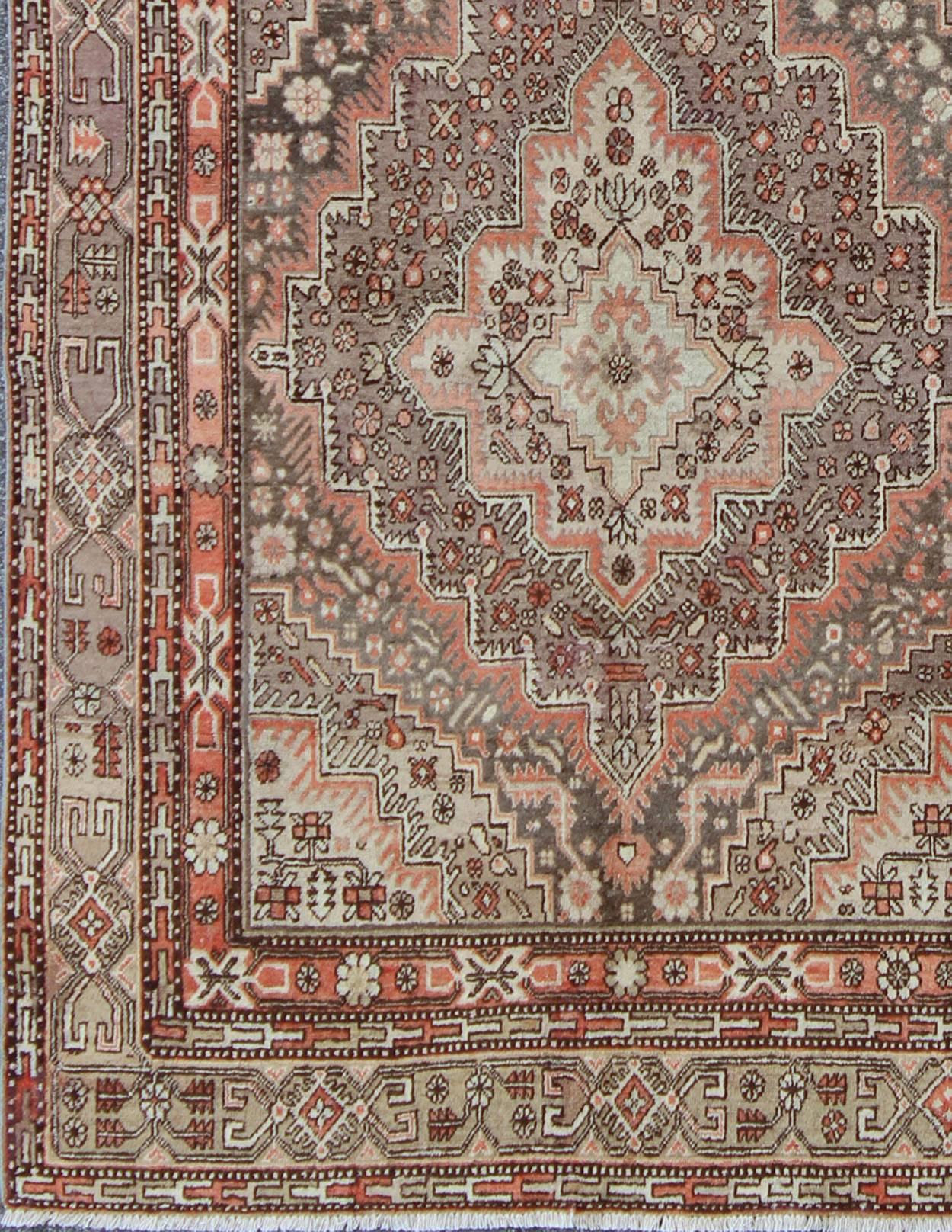 This beautiful Khotan rug from East Turkestan has a wonderful, light purple border that imbues it with an Asian aesthetic. The border is encased by two guard borders, featuring a multicolored Greek key design. The field has two large medallions