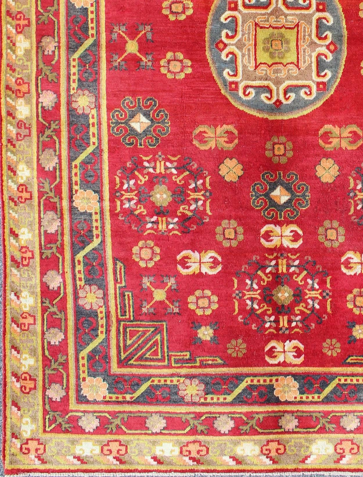 This attractive vintage Khotan rug is a spectacular testament to the complexity of Turkestan design. The red of the central field plays host to a stunning display of the entwined tree of life bearing budding blossoms and luscious pomegranates. The