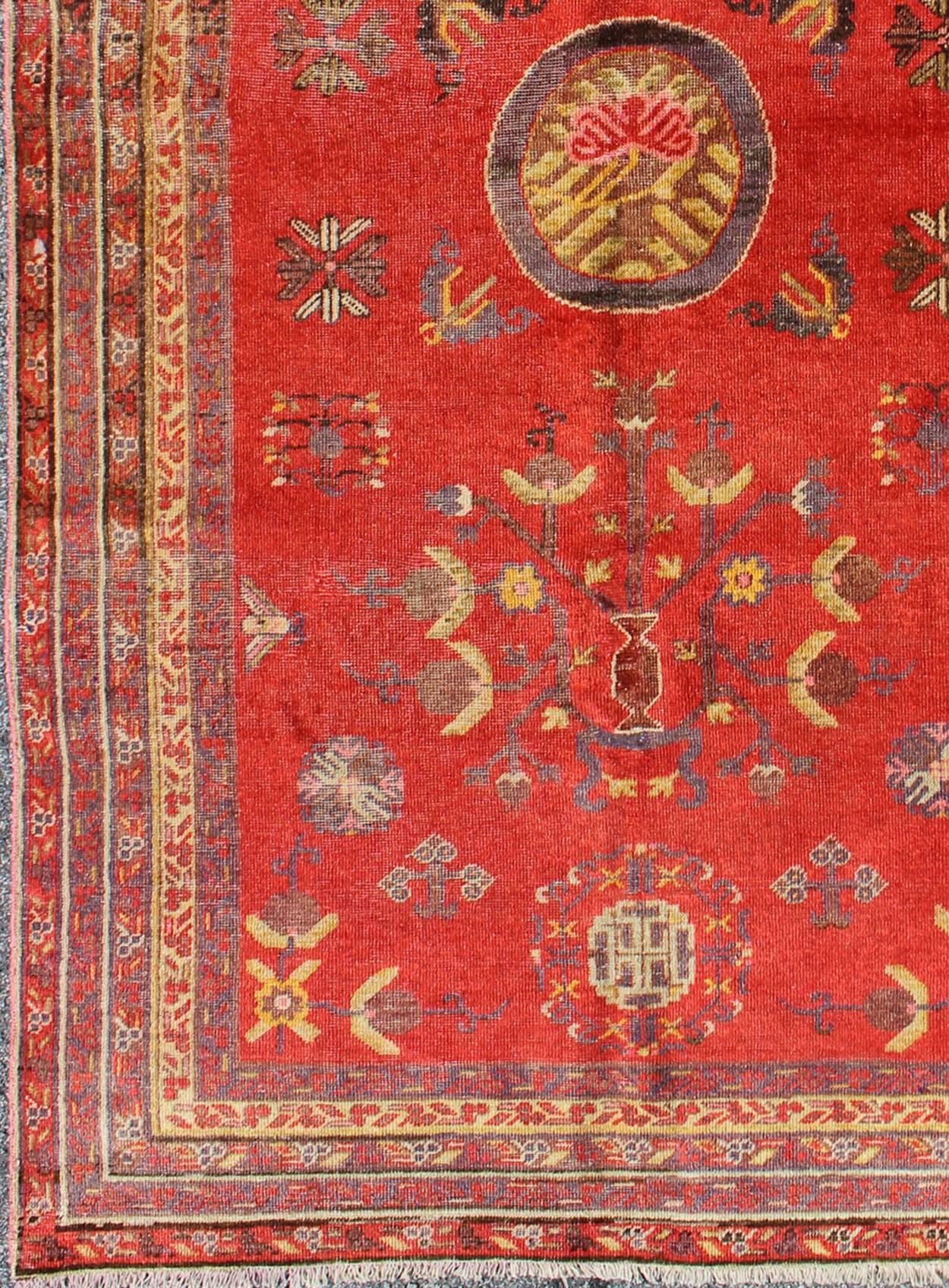 Mesures : 4'1'' x 8'6''.
Cet attrayant tapis antique de Khotan est un témoignage spectaculaire de la complexité du design du Turkestan. Le rouge du champ central accueille un magnifique arbre de vie entrelacé portant des fleurs en bouton et de