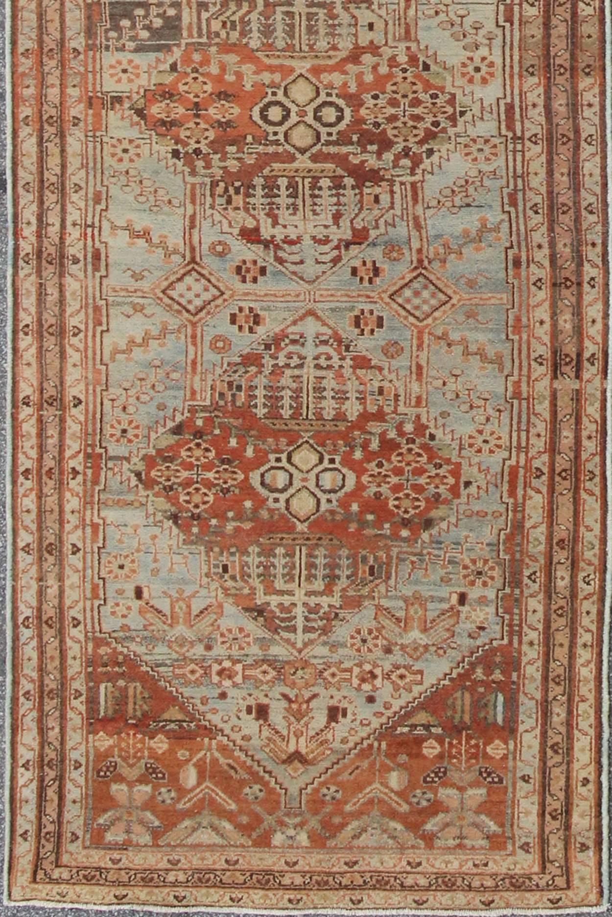 This magnificent antique Persian Malayer carpet, of an impressive size, bears a beautiful, all-over Sub-geometric design paired with a delightful palette of burnt orange, various blues and a very light peach. The central field is filled with a