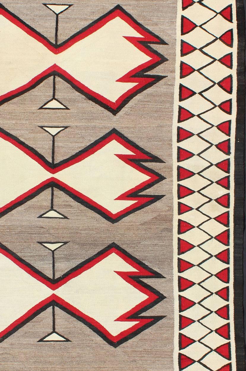 This beautiful antique Navajo textile is from the Ganado region and features a carded gray field with aniline-dyed red and black diamond crosses. The unique border of ivory has a repeating tribal pattern of red and black.
 
Measures 4'2'' x
