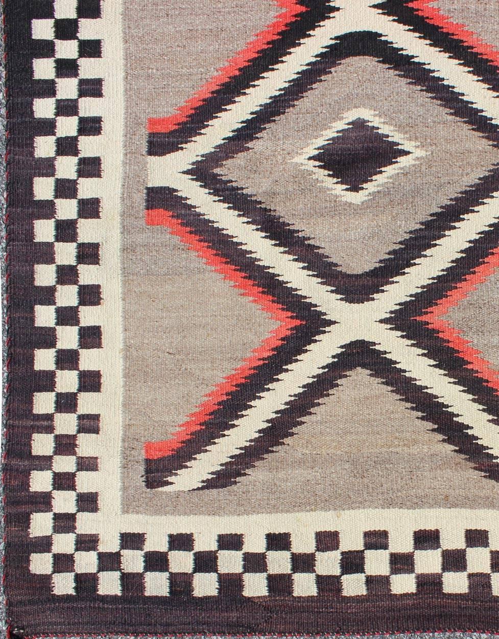 This intriguing vintage Navajo rug was woven in the United States during the first half of the 20th century. The exciting and unique composition boasts a captivating geometric composition with an all-over diamond design. The range of colors includes