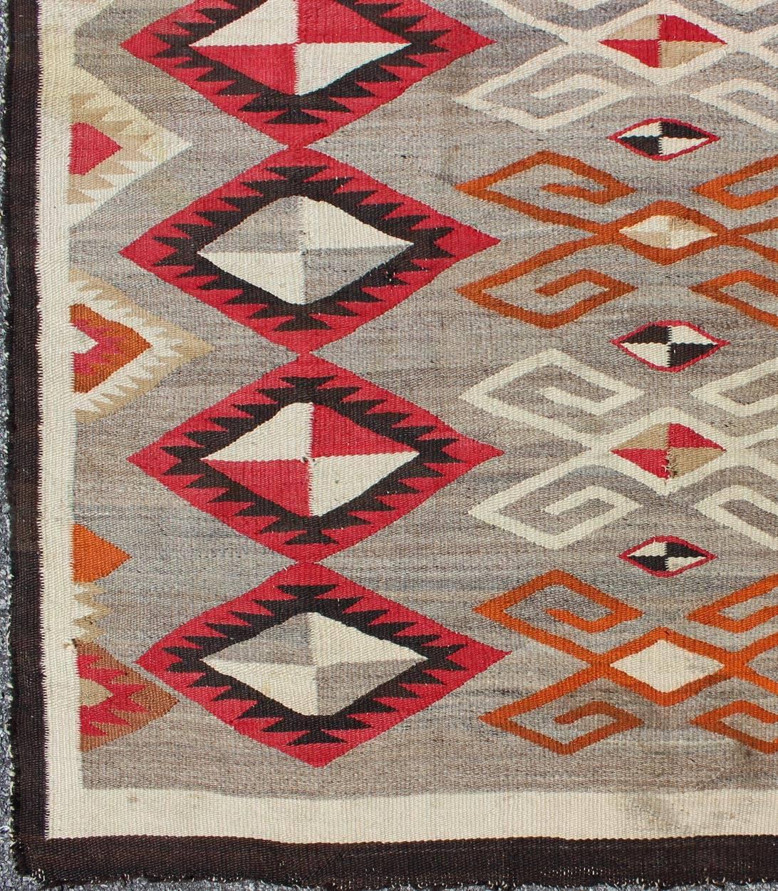 This intriguing antique Navajo rug was woven in the United States during the first half of the 20th century. The exciting and unique composition boasts a captivating geometric composition with an all-over diamond design. The range of colors includes
