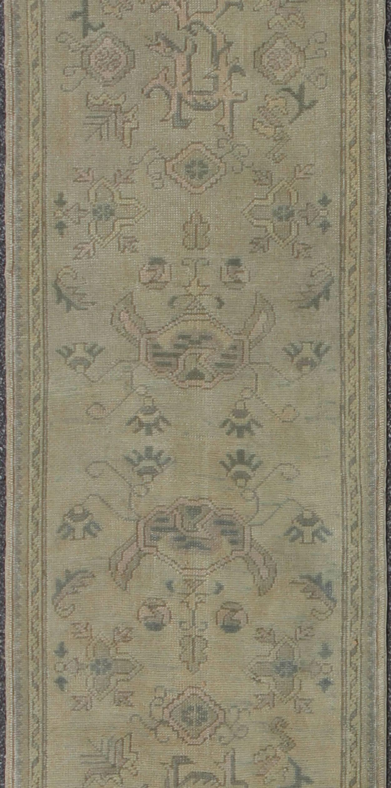 Measures: 2'10 x 12'8.

This 1930's antique muted Oushak runner rests beautifully upon a field of elegant cream and taupe. An all-over pattern takes center stage and is well balanced by motifs composed of various cool colors. Multiple borders of