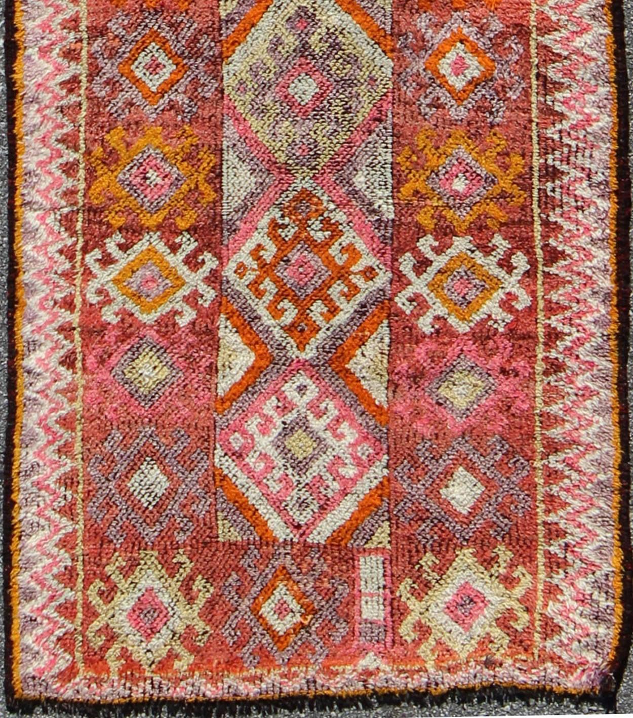 Dimensions: 2'11 x 9'4.
This geometric and tribal rug demonstrates an ostentatious side of modern design Turkish weaving. The various shades of red, softened by age, pair elegantly with the bold tones of scarlet, orange and charcoal, laid out
