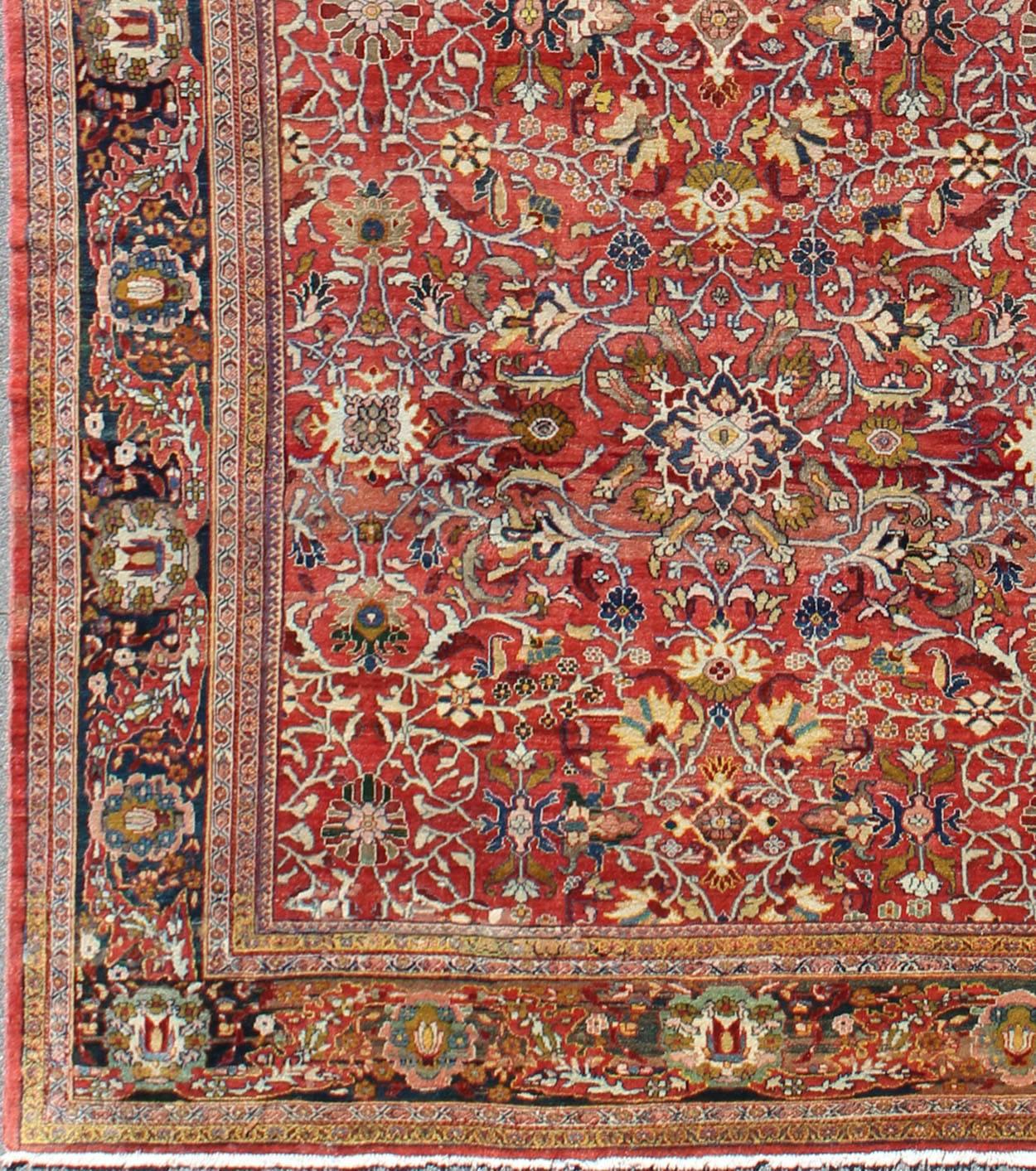 This beautiful Sultanabad rug features a soft red field, which bears an intricate floral motif of repeating red, blue, ivory, green, yellow, peach, and light blue flowers. A blue border displays single flower blossoms interspersed with palmettes