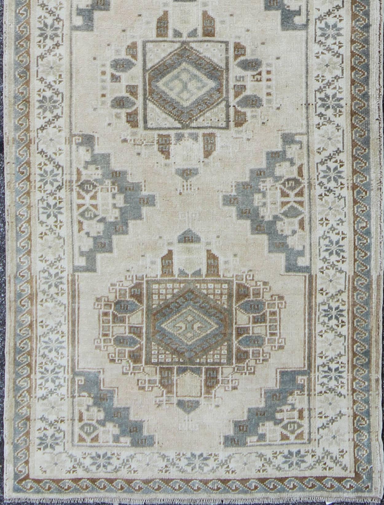 Measures: 3'4'' x 12'2''.
This beautiful vintage Oushak runner from mid-20th century Turkey features a Classic Oushak design, which is enhanced by lustrous wool. The faint ivory ground is home to five large and elegant taupe and gray medallions. The