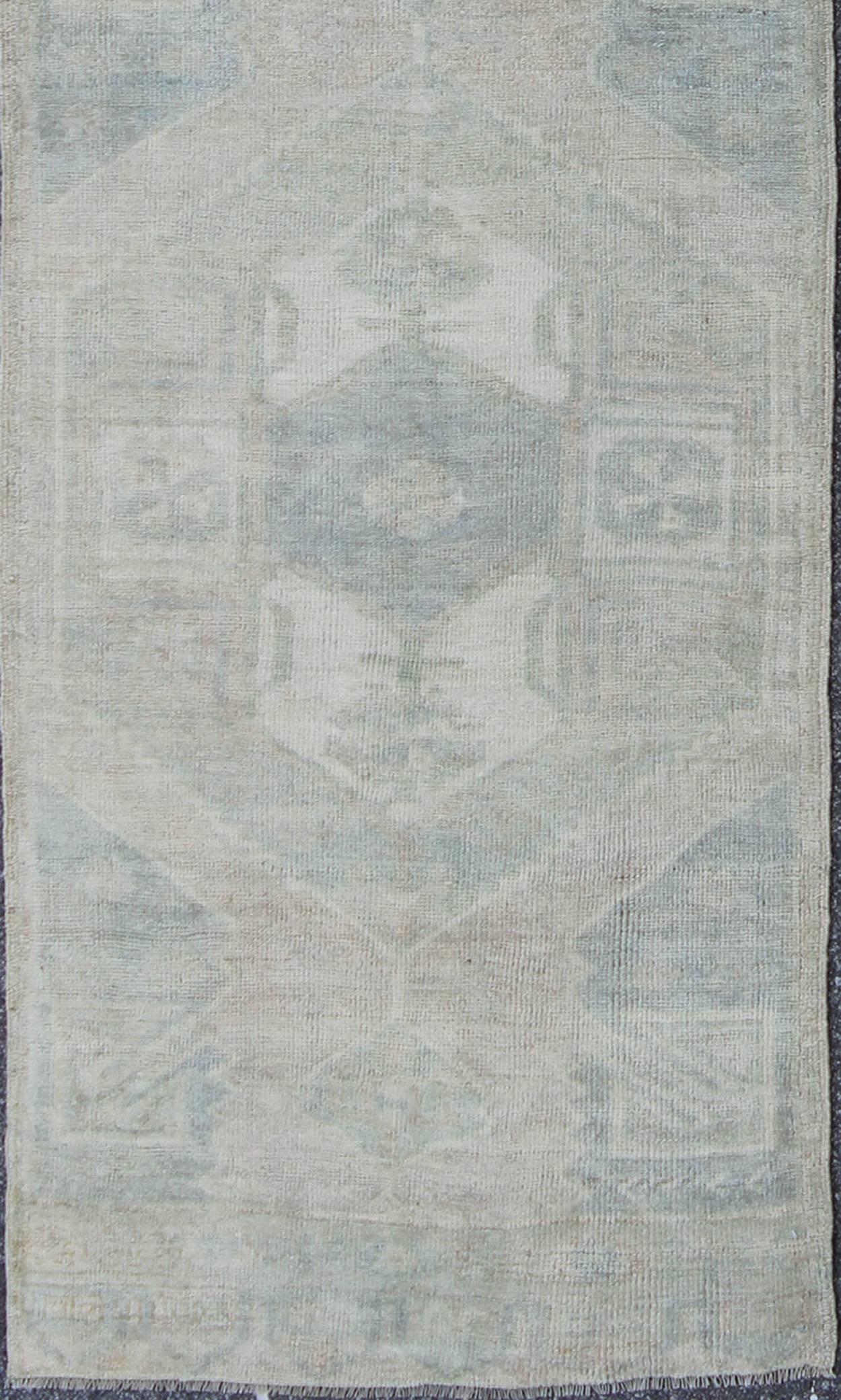 Measures: 3'3'' x 12'0''.
This beautiful vintage Oushak runner from mid-20th century Turkey features a Classic Oushak design, which is enhanced by lustrous wool. The faint ivory ground is home to two large and elegant medallions of taupe and light