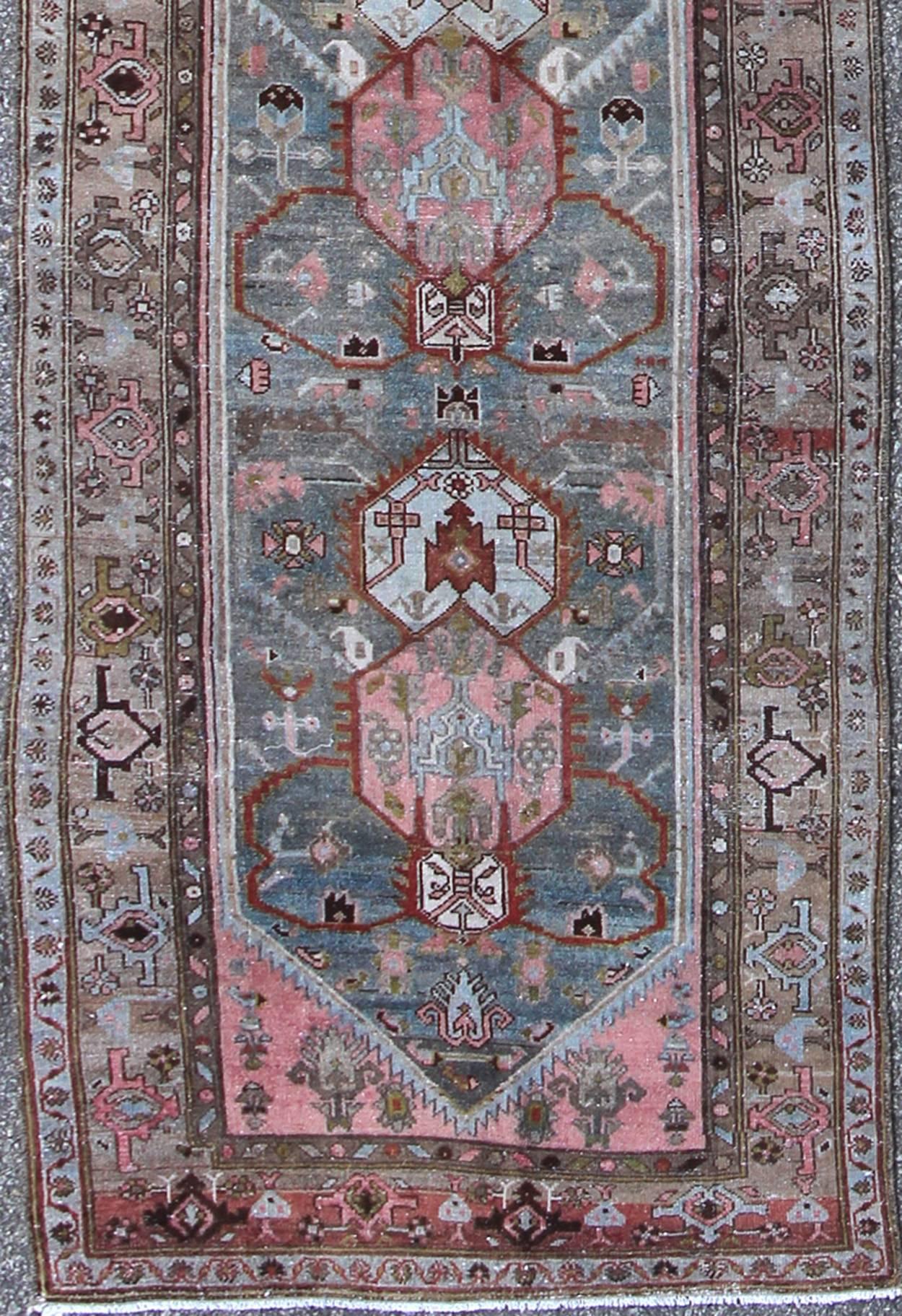 This magnificent antique Persian Malayer runner, of an impressive size, bears a beautiful, all-over sub-geometric design paired with a delightful palette of various shades of light blue, pink, red, ivory, pea green, and taupe. The central field is