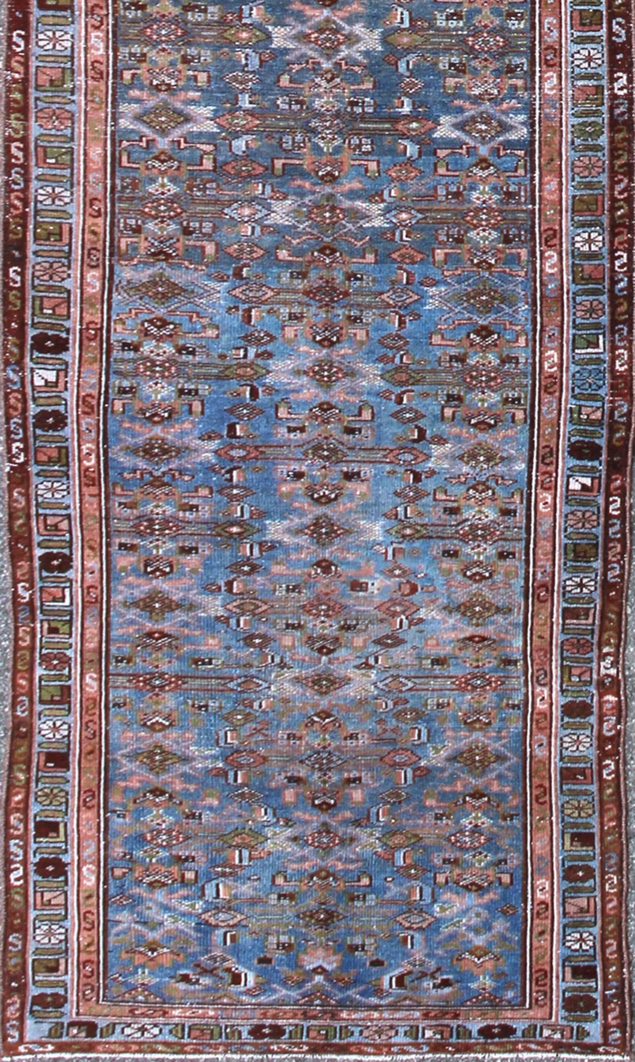 This antique Kurdish tribal runner was woven by Kurdish weavers in western Persia in the early 20th century. Often they used this repeating latch-hook design in the border, woven along in varying colored panels. The emphasis with these rugs is on