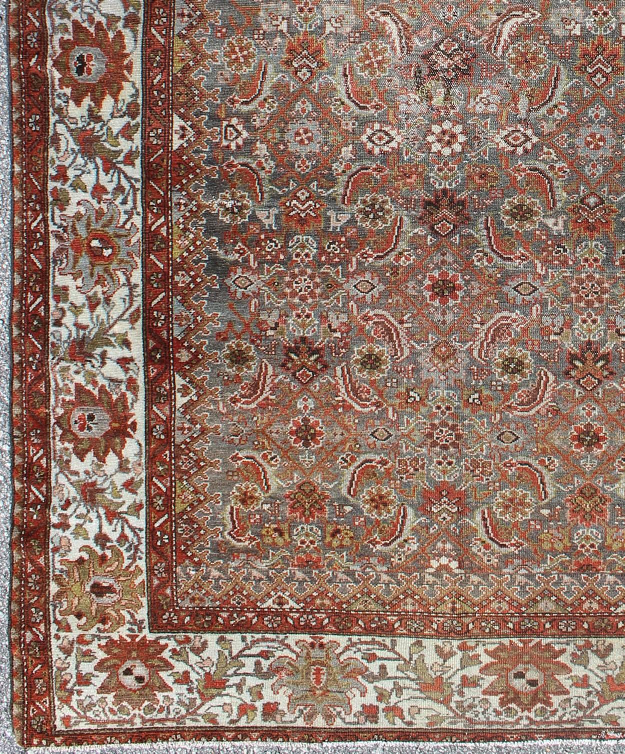 This magnificent antique Persian Malayer carpet bears a beautiful, all-over sub-geometric design paired with a delightful palette of various shades of light blue, deep red, and taupe. The central field is filled with a dazzling display of various