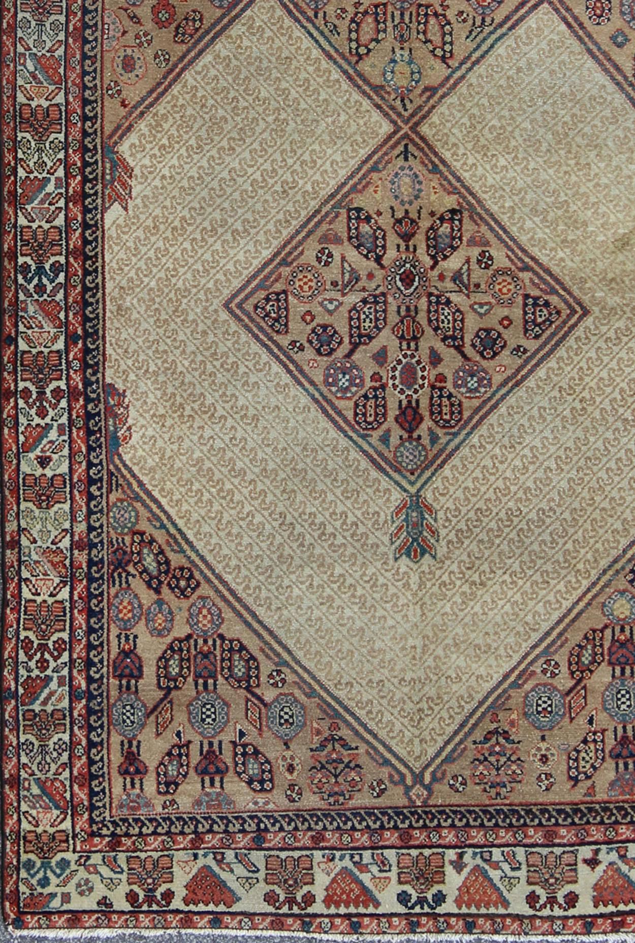 This beautiful antique late 19th Century Persian Serab runner rests on a camel background, which surrounds the three diamond medallions of alternating ivory, red, and blue colors. The main border is composed of ivory with a repeating geometric