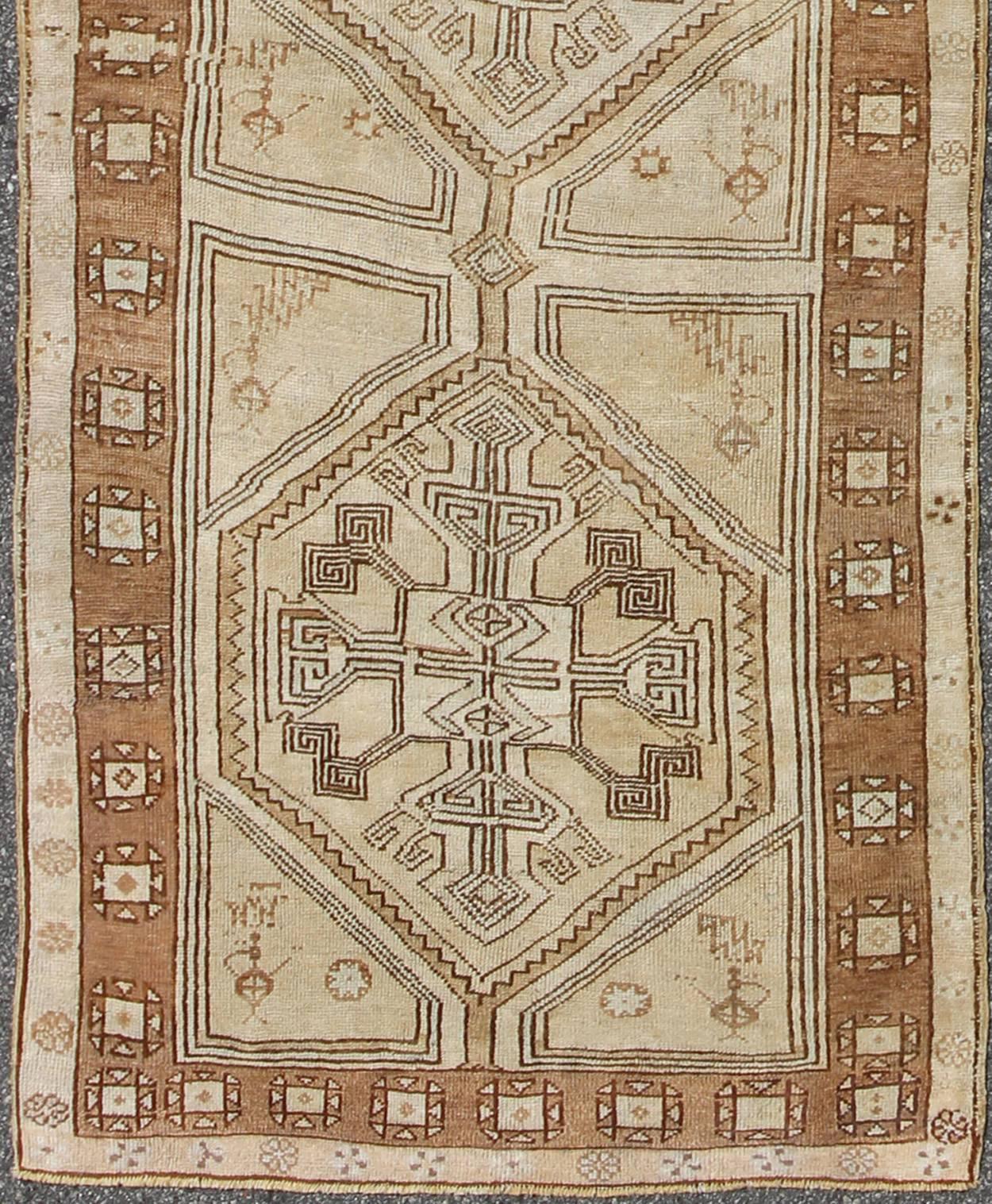 Brown, camel, ivory long Turkish Oushak runner with geometric tribal medallions, rug en-142368, country of origin / type: Turkey / Oushak, circa mid-20th century.

This vintage Turkish Oushak gallery rug, (circa mid-20th century) features a unique