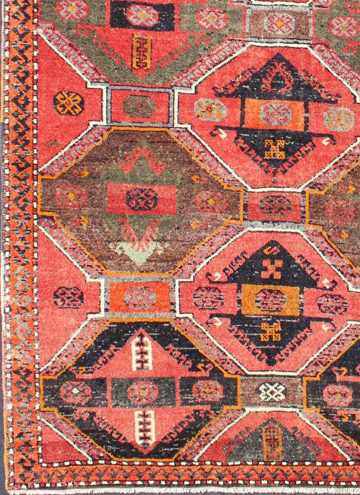 Measures: 3'10'' x 6'9''.
This Turkish Oushak gallery rug (circa mid-20th Century) features an assortment of geometric medallions that take center stage on a bright red field. The border reveals a design with tribal inspiration rendered in soft