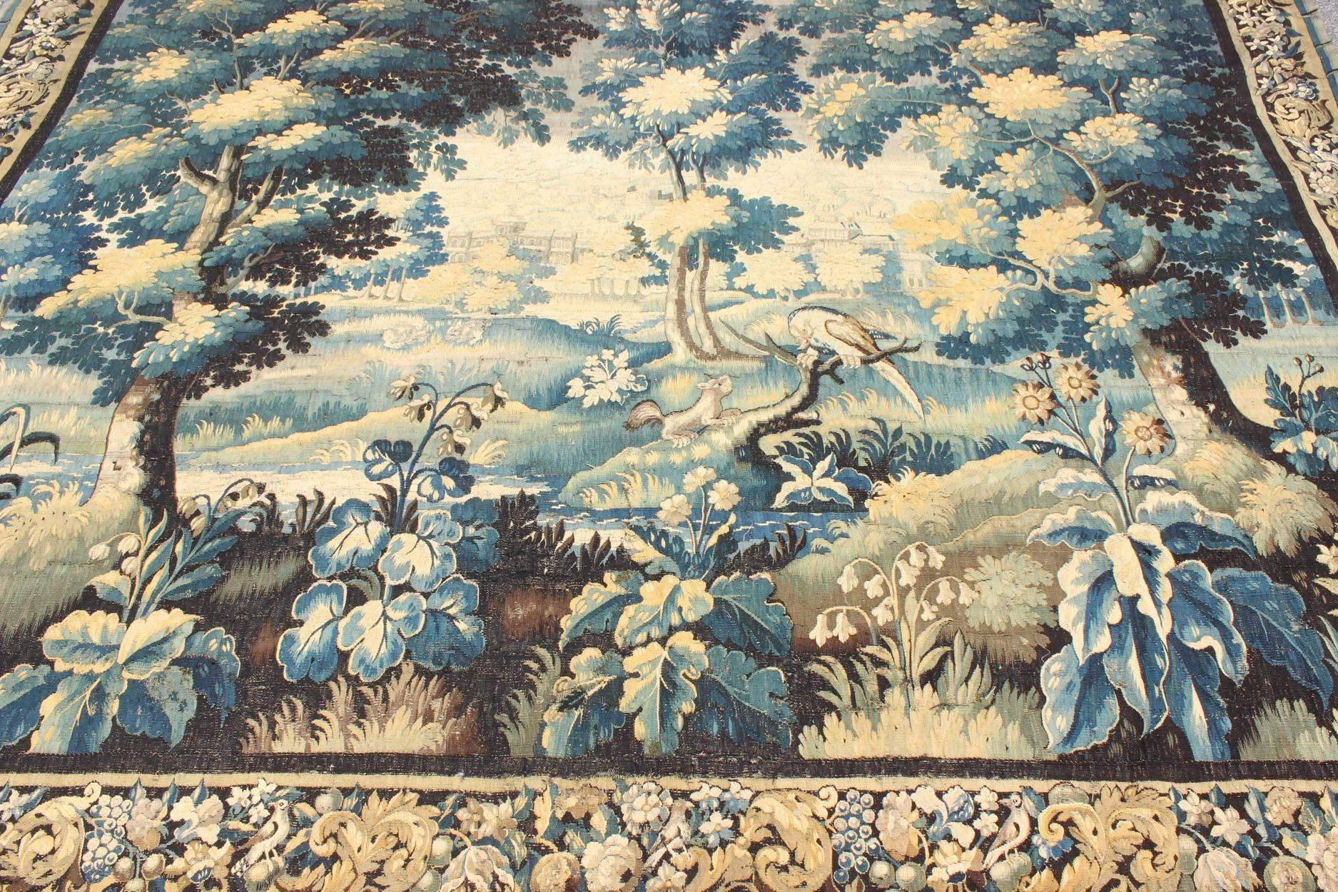 French 17th Century Antique Tapestry with Woodland Scene and Floral Border in Blue Tone For Sale