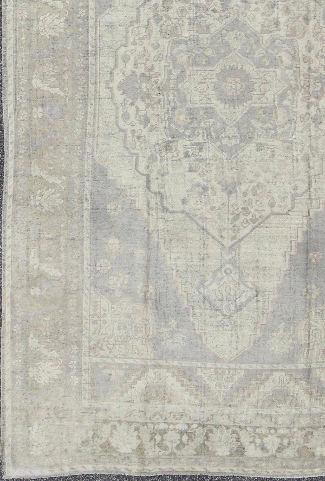 Vintage Oushak in Muted Colors of Gray, Taupe, Cream and Light Brown.
This softly muted Oushak carpet rests beautifully upon a field of elegant grey and taupe. A large medallion takes center stage and is well balanced by four prominent organic