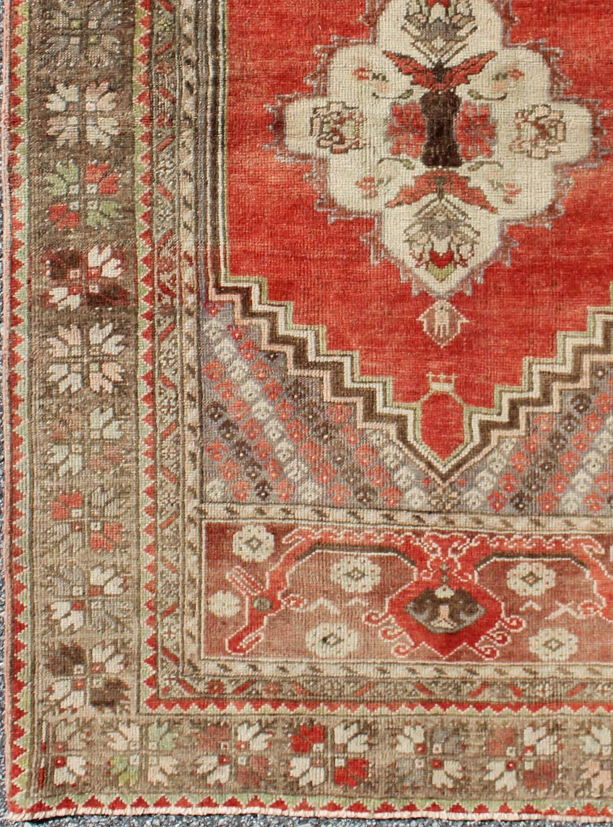 This antique Oushak bears a stylized medallion that commands the center field. A broad border of repeating motifs and floral patterns enclose the entire rug. Coral and light green colors complement the light brown, sub-geometric border. 

Turkish