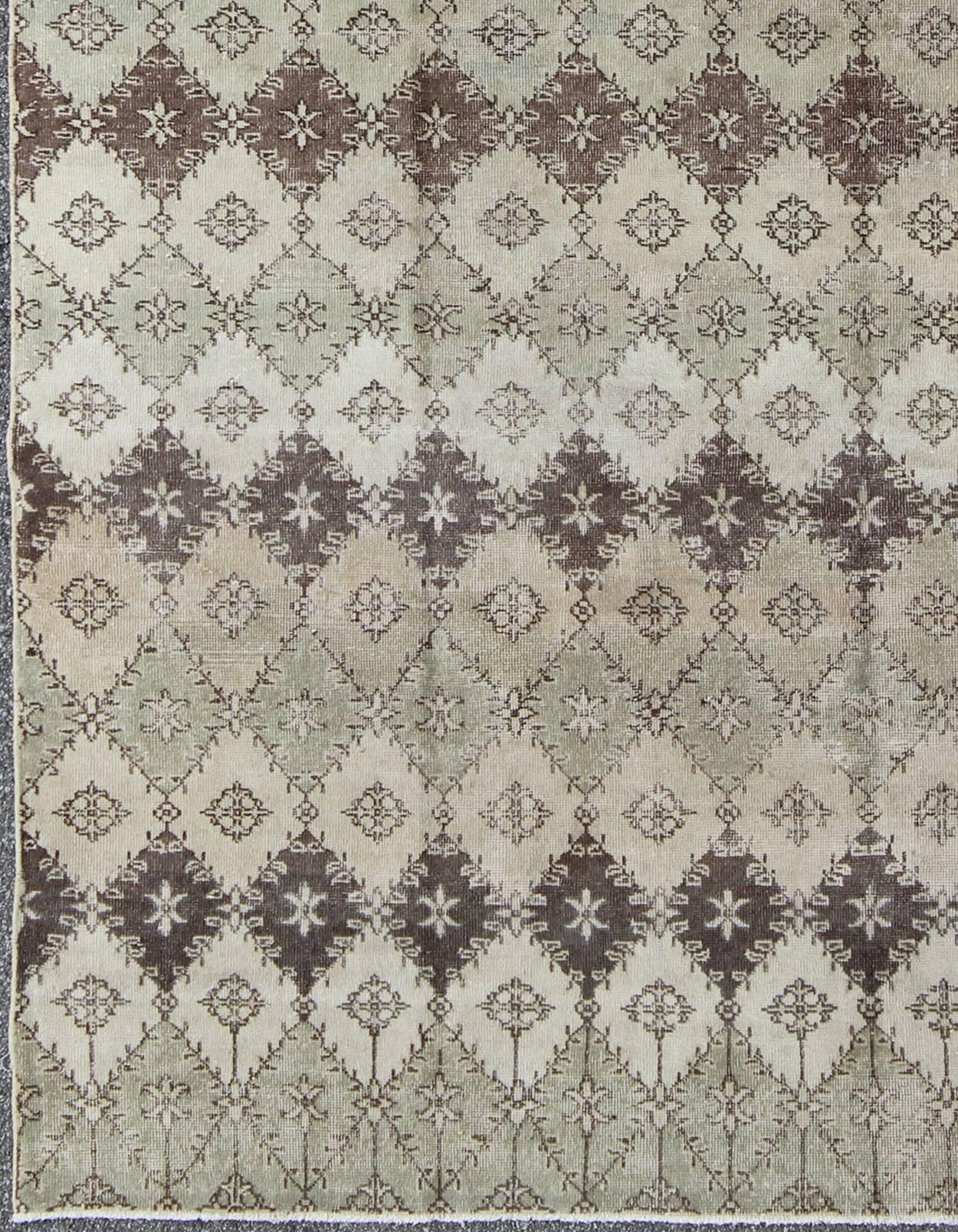 This vintage Turkish Mid-Century Modern distressed rug is rendered in diamond pattern and a speckled assortment of taupe, light blue, muted green, Chocolate Brown and gray, this Deco style carpet has a unique design and color combination that makes