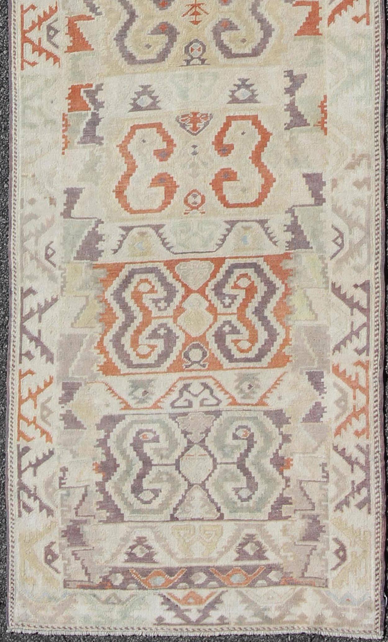 Unique Turkish Runner with Geometric and Tribal Elements.
This long and unique Oushak carpet rests beautifully upon a field of elegant golden and taupe colors. The large medallions are composed of various colors of blues, reds, taupe, rust and
