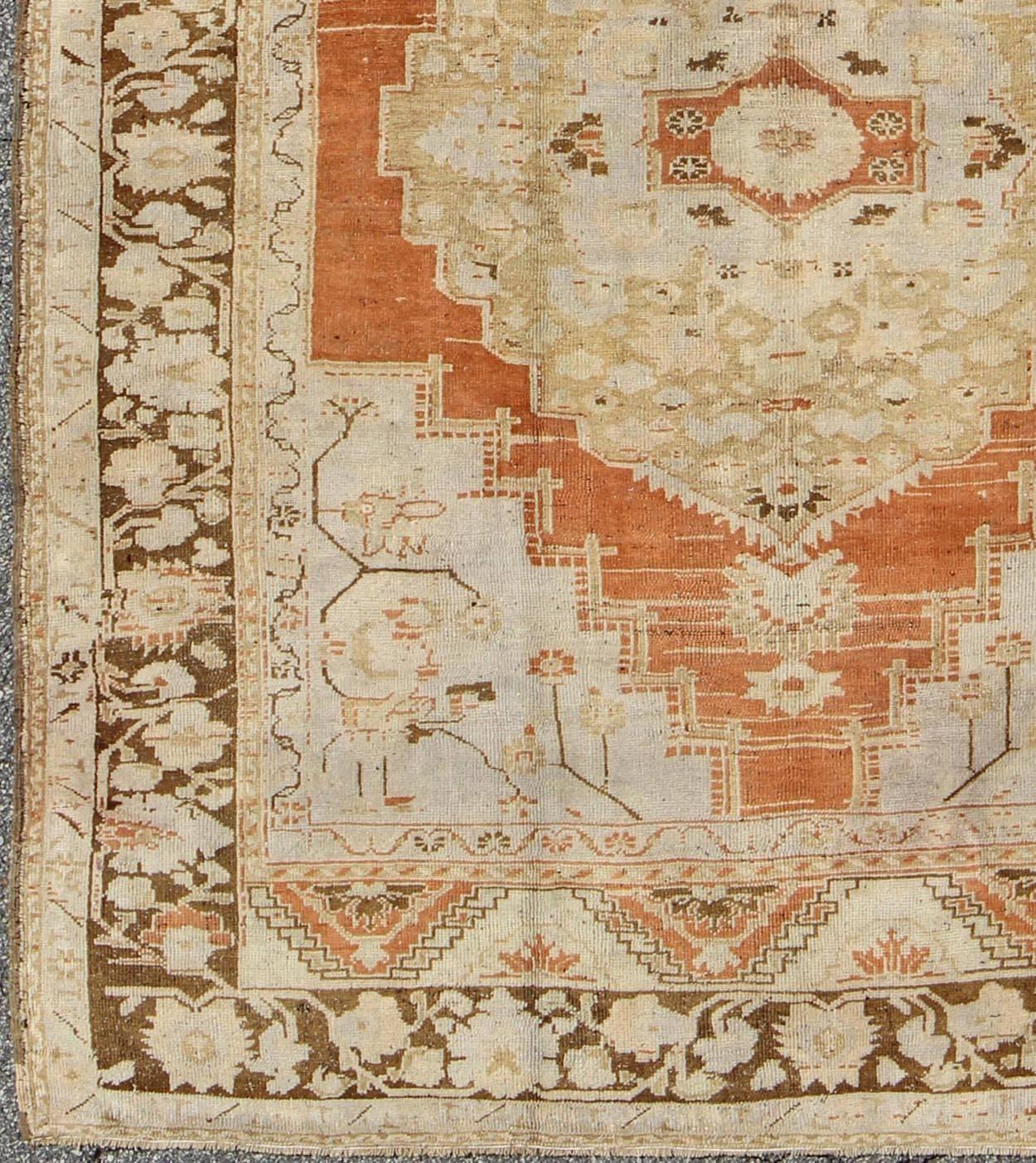 Vintage Turkish Oushak Rug in Light Orange, Light Blue, Gray and Brown.
This vintage Oushak carpet rests beautifully upon a field of soft orange, light gray and taupe colors. A medallion of green and neutrals takes center stage and is well balanced