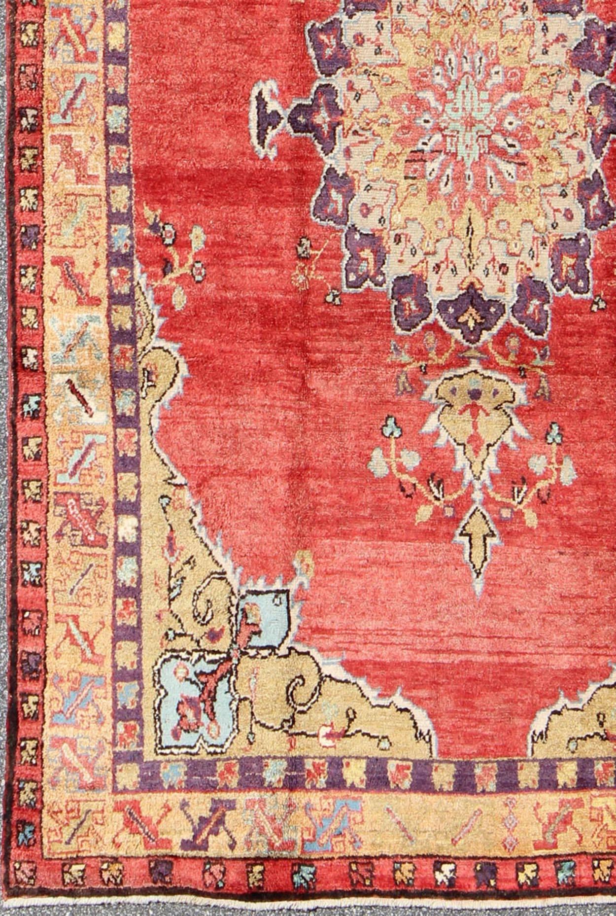 Colorful Vintage Turkish Oushak Rug with Red and Gold Colors.
This colorful Oushak carpet rests beautifully upon a field of elegant red. A large medallion of brown, taupe, purple and gray takes center stage and is well balanced by four prominent