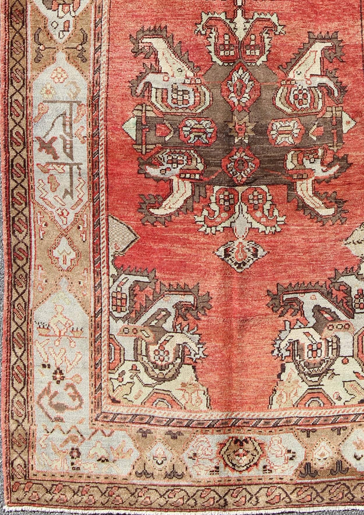 This softly colorful Oushak carpet rests beautifully upon a field of elegant light coral. Two large medallions of brown, taupe and gray take center stage and are well balanced by four prominent organic corner motifs composed of various muted gray