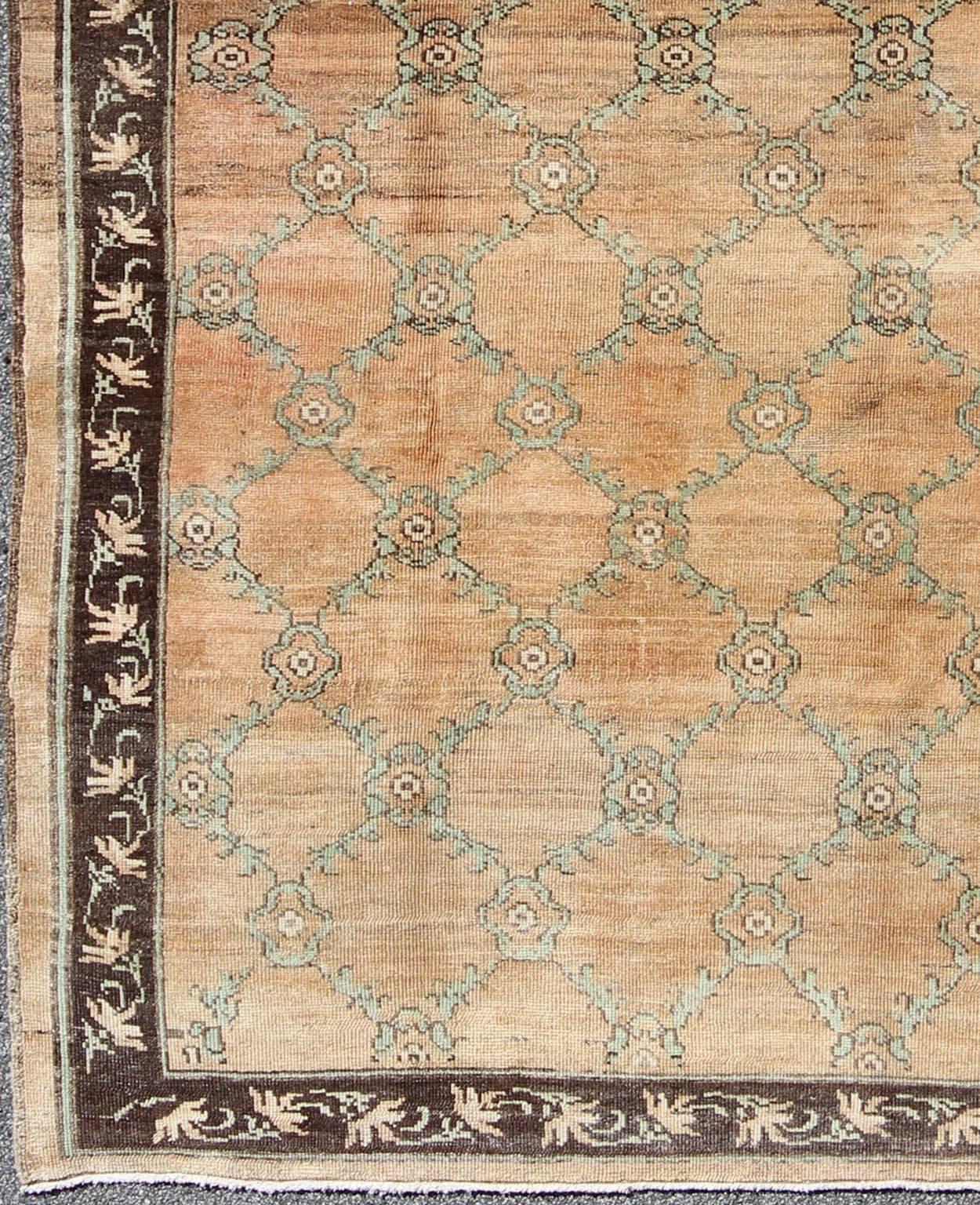This magnificent Oushak beautifully illustrates the impressive craftsmanship and design of Turkish weavers. The muted design of repeating flowers in light green on a orange background flows through the rug's center field. Linear flower branches in