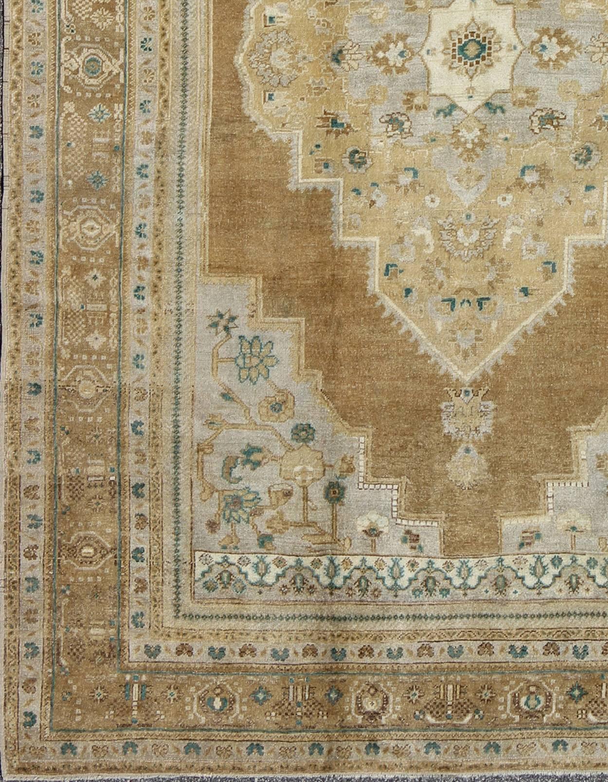 Vintage Oushak Turkish Rug in Light Golden Brown, Gray/Blue and Teal Accents.
This magnificent Oushak beautifully illustrates the impressive craftsmanship and design of Turkish weavers. The muted design gives the illusion of the large medallion