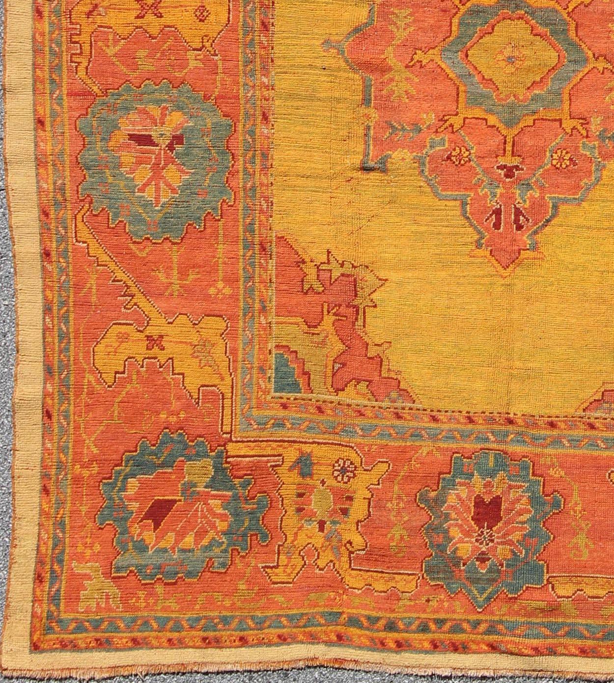Antique Turkish Oushak Rug in  Saturated Gold, Orange Colors and Blue Accent.
Fashioned during the turn of the 20th Century, this unusual antique Oushak bears a remarkable geometric design paired with a delicately understated palette. An saffron