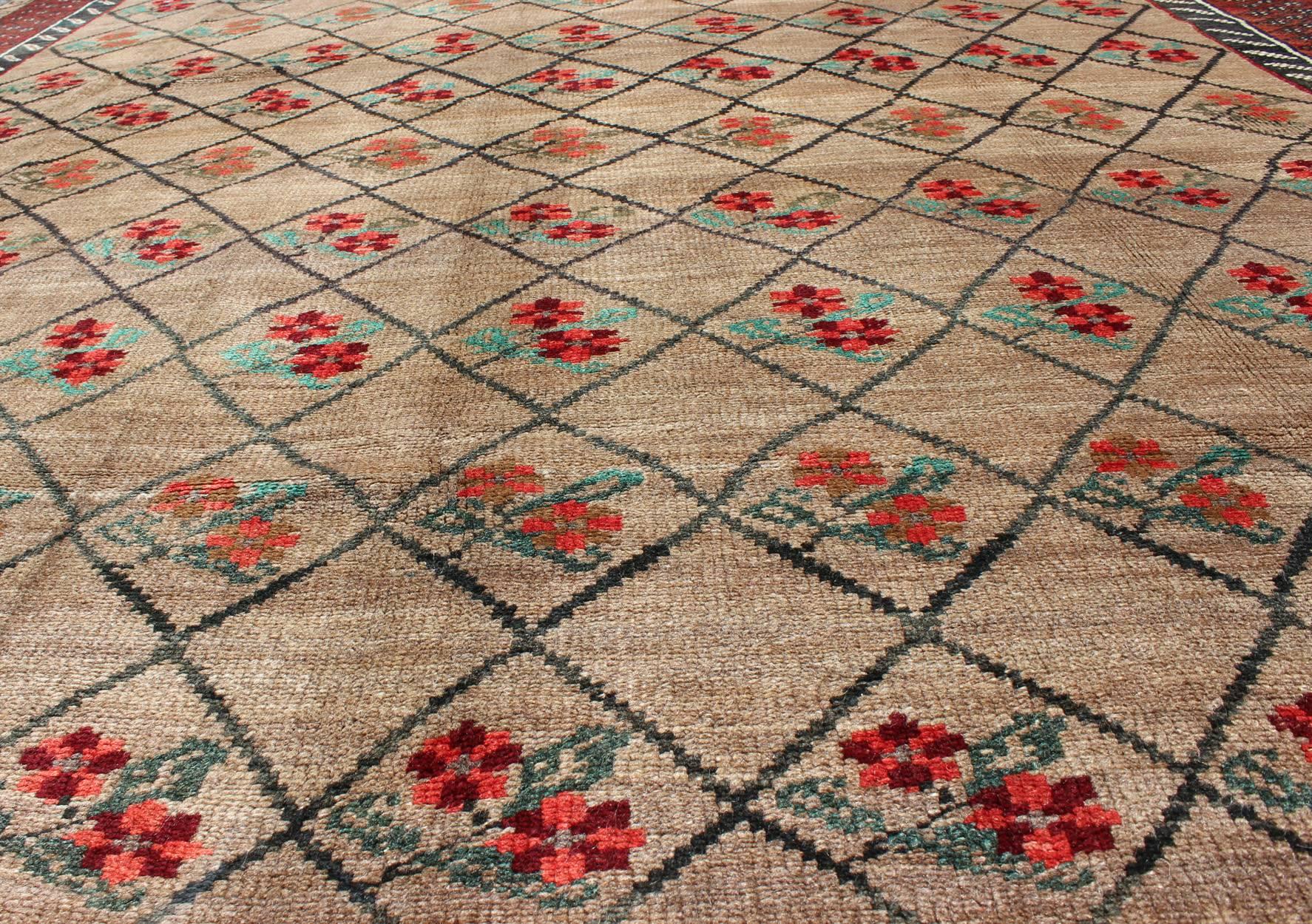 This colorful Turkish carpet rests beautifully upon a field of camel and light brown. A repeating flower pattern of taupe, green and gray takes center stage and is well balanced with a broad border that gently surrounds the center field. Natural