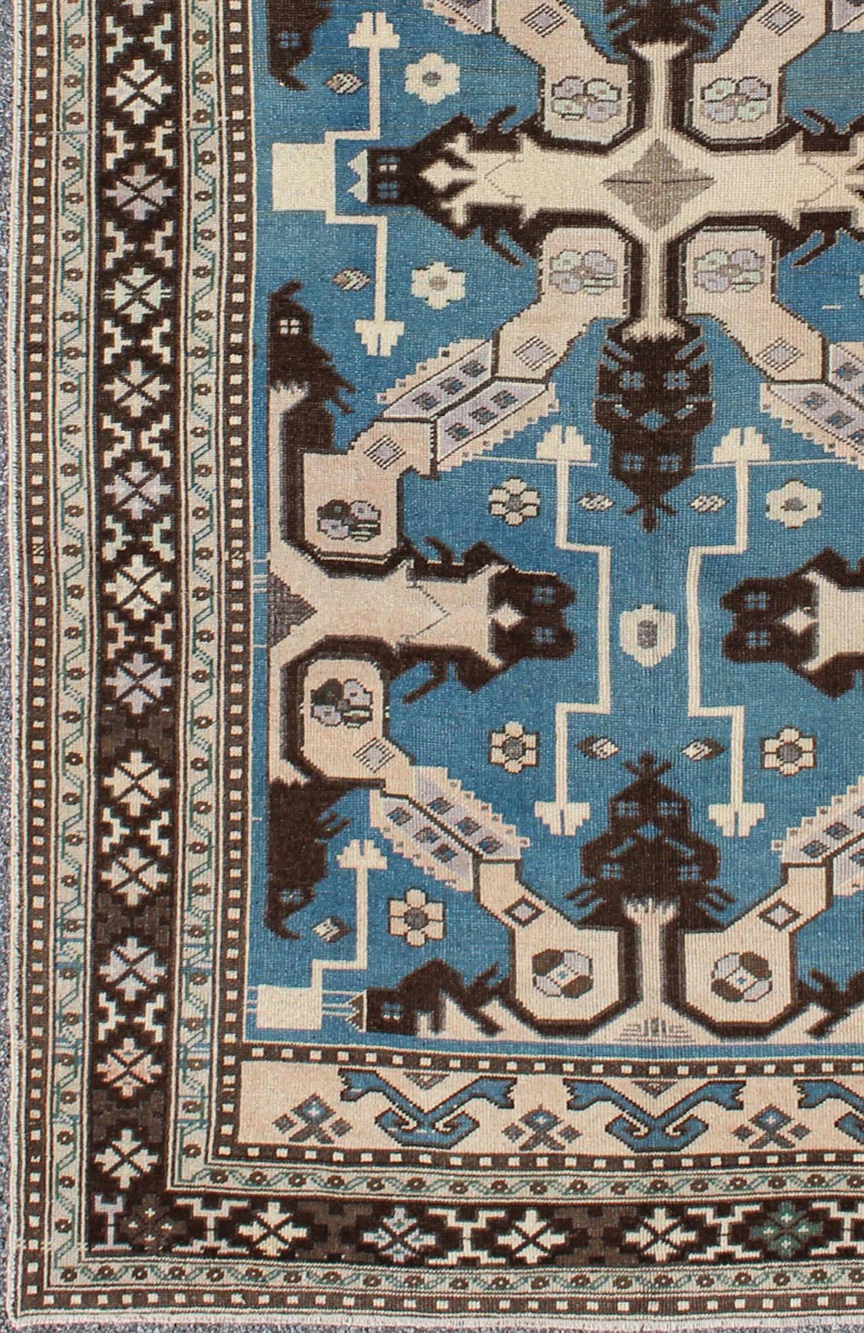 This stunning Turkish rug features a large geometric design and a unique color combination. Set on a steel blue background, this Turkish rug has variegated colors of brown, taupe and other neutral hues, rendering a magnificent fit for a wide variety