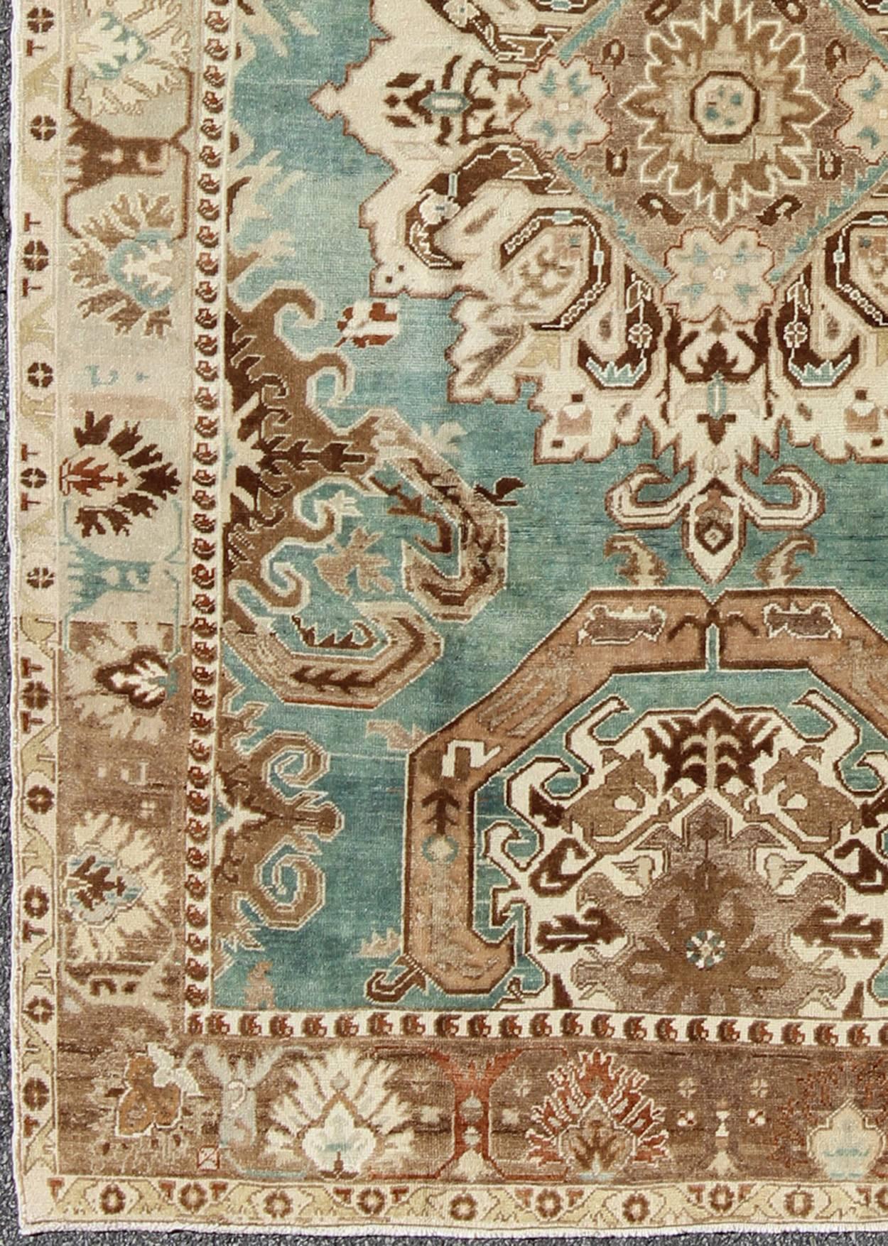 Situada sobre un singular campo turquesa, esta impresionante alfombra turca muestra un atrevido diseño con tonos marrones, topo, marfil, verde espuma de mar y otros neutros. Estas asombrosas combinaciones hacen que esta alfombra se adapte