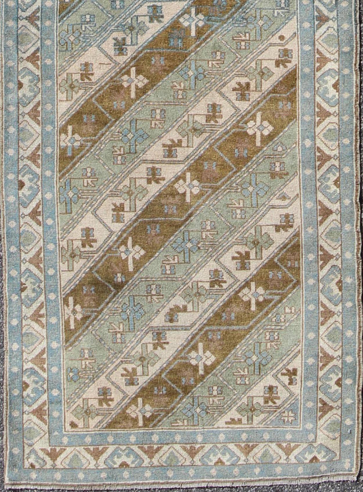 This striking Turkish Oushak rug features a bold collection of geometric motifs and colorful small flowers that combine to form a contemporary and exceptionally graphic repeating pattern. The border composition features a robust pattern of green,