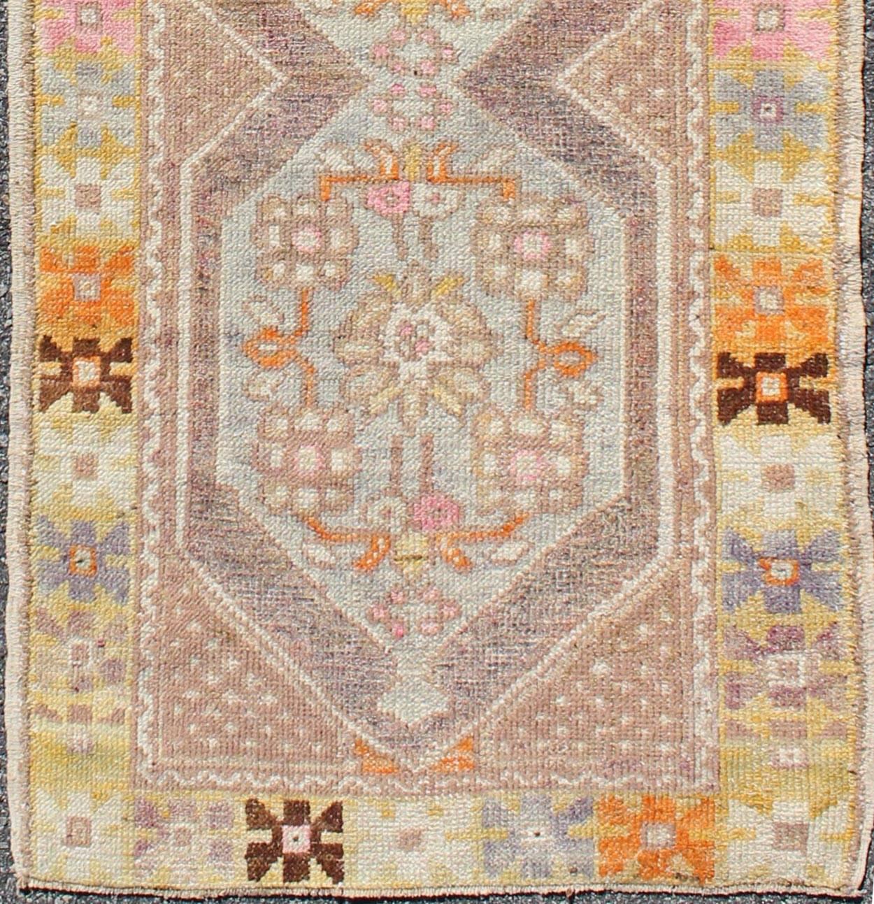 This beautifully colored Oushak rug contains subtle tones of lavender, coral, taupe, brown, beige, orange, pink, soft gold, light blue and green, which are highlighted by chocolate and mocha colors. The stylized geometric medallions accentuate a