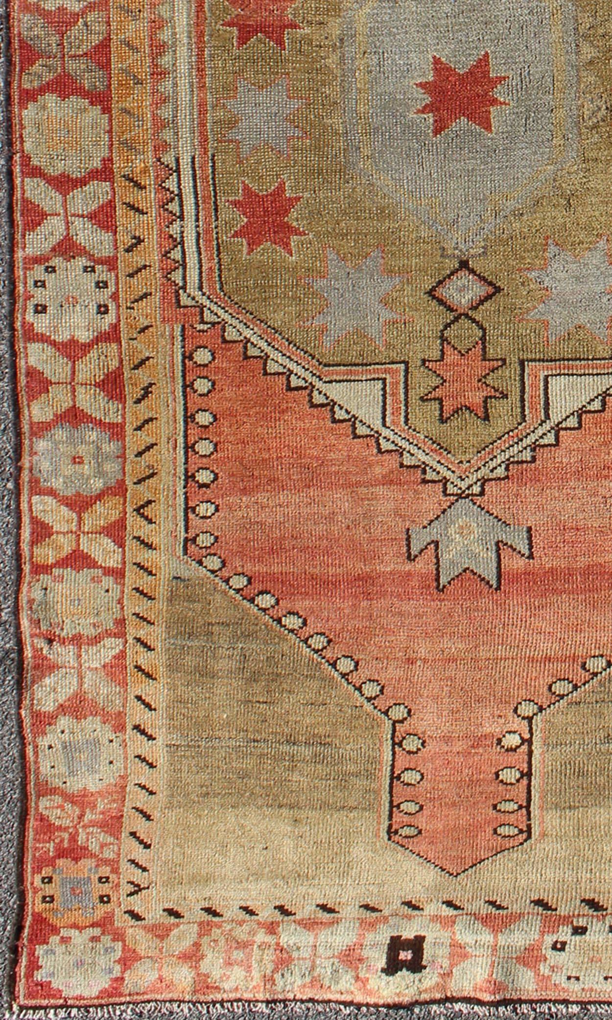 Vintage Turkish Oushak Rug in Faded Red, Camel, Light Blue.
This lovely Oushak features an unusual center medallion in light green with a coral central field, characterized by floral blossoms and trellis motifs. The softly-hued coral border repeats