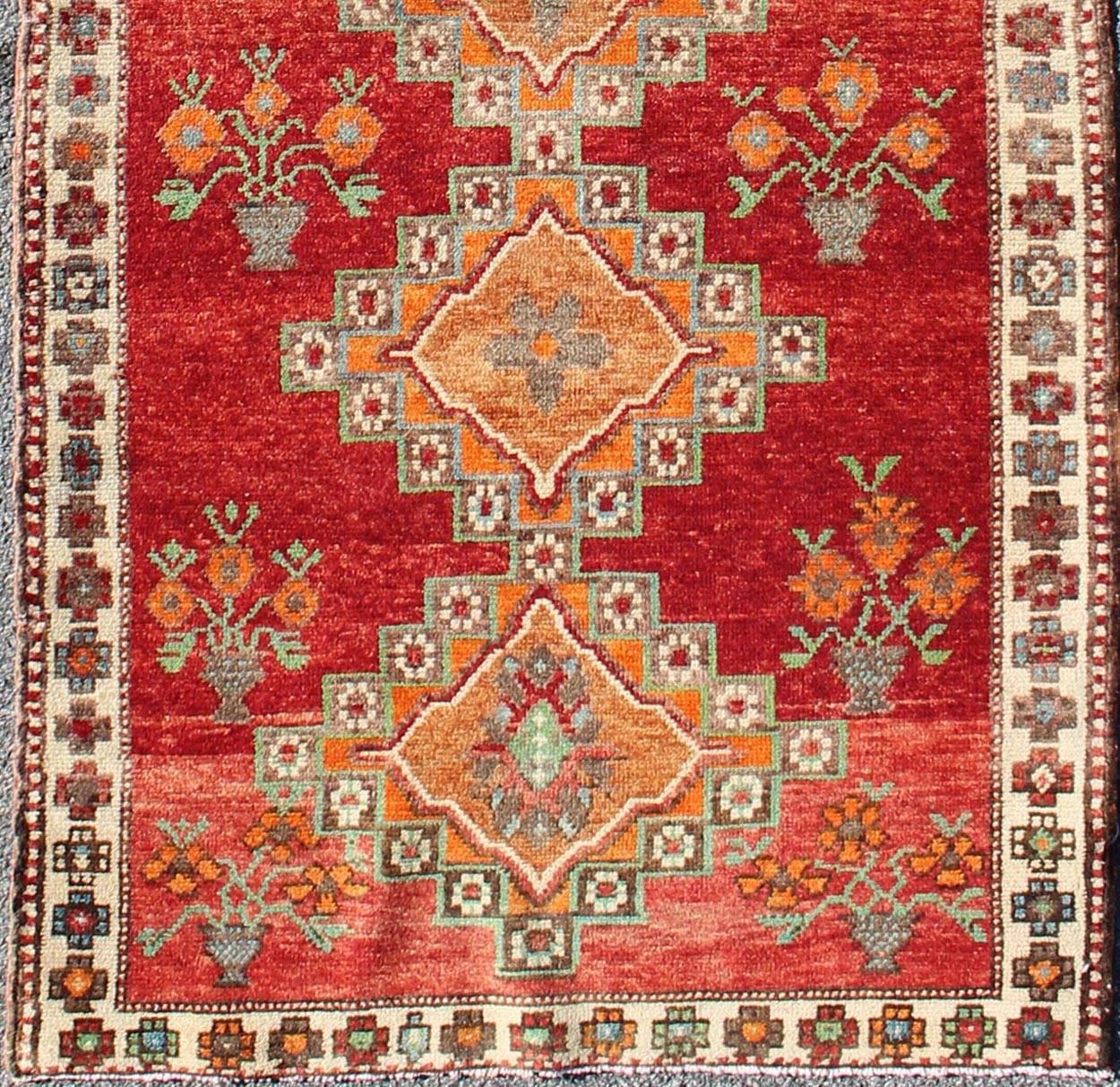 This vintage Oushak runner features a unique blend of cheerful colors and an intricately beautiful design. The multi-layered diamond medallions are complemented by a symmetrical set of floral motifs. The various shades of blue, green, and chocolate