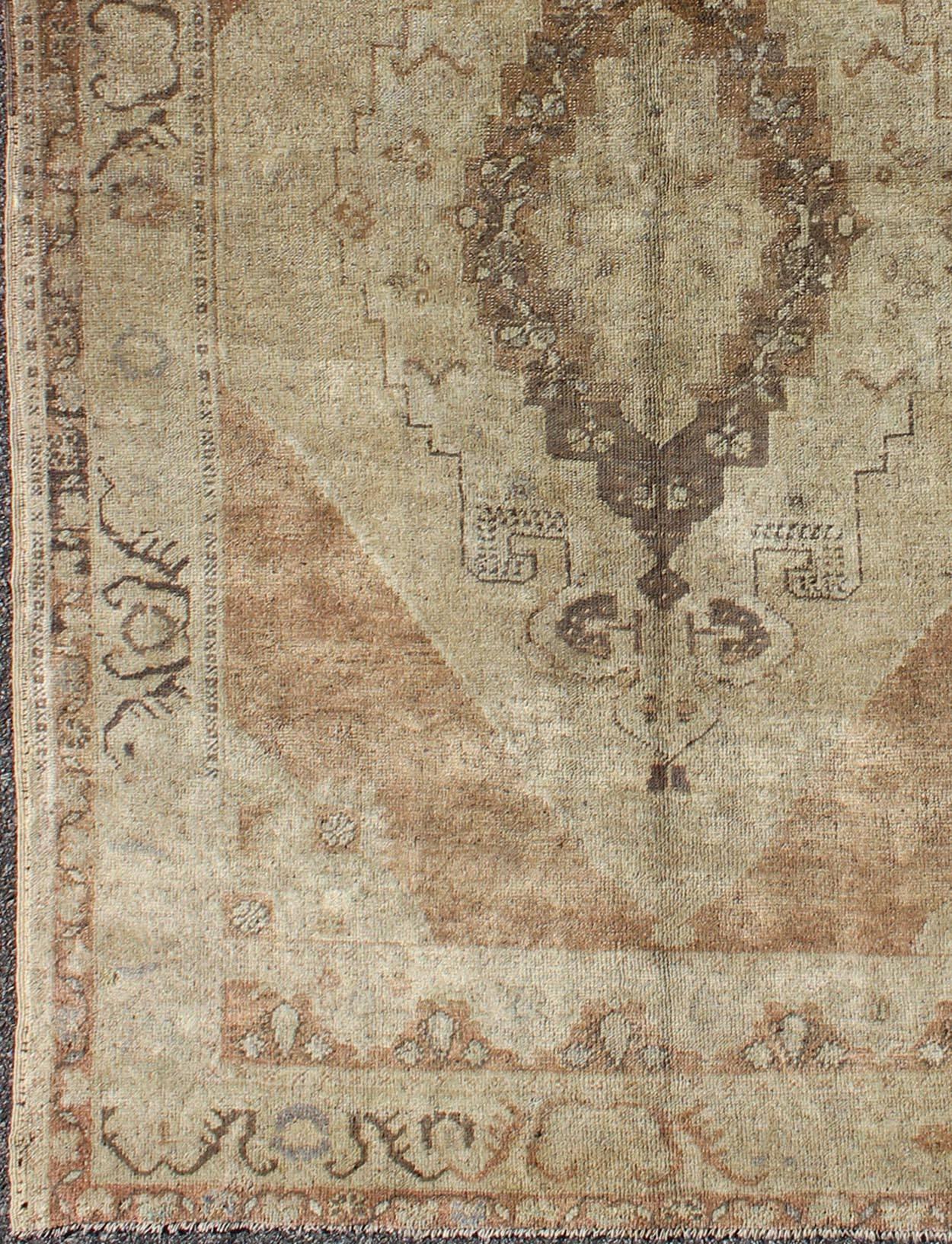 This uniquely colored Oushak contains subtle tones of taupe, beige and green, which are highlighted by charcoal and mocha colors. The elegant center medallion accentuates a botanic theme and is surrounded by defined outlines. Through both