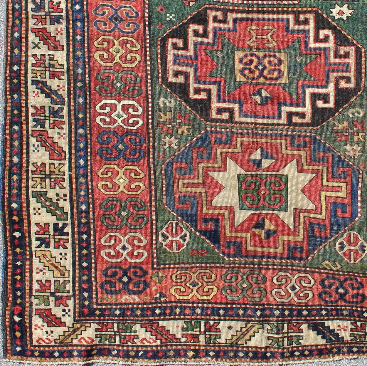 Measures: 5'5 x 7'1.

This antique Kazak, from the late 19th century, showcases three distinctive medallions that identify it as an antique Kazak. The field pattern has latch hooks mandalas consistent with Kaza-Bordjalou, the green ground and boxed