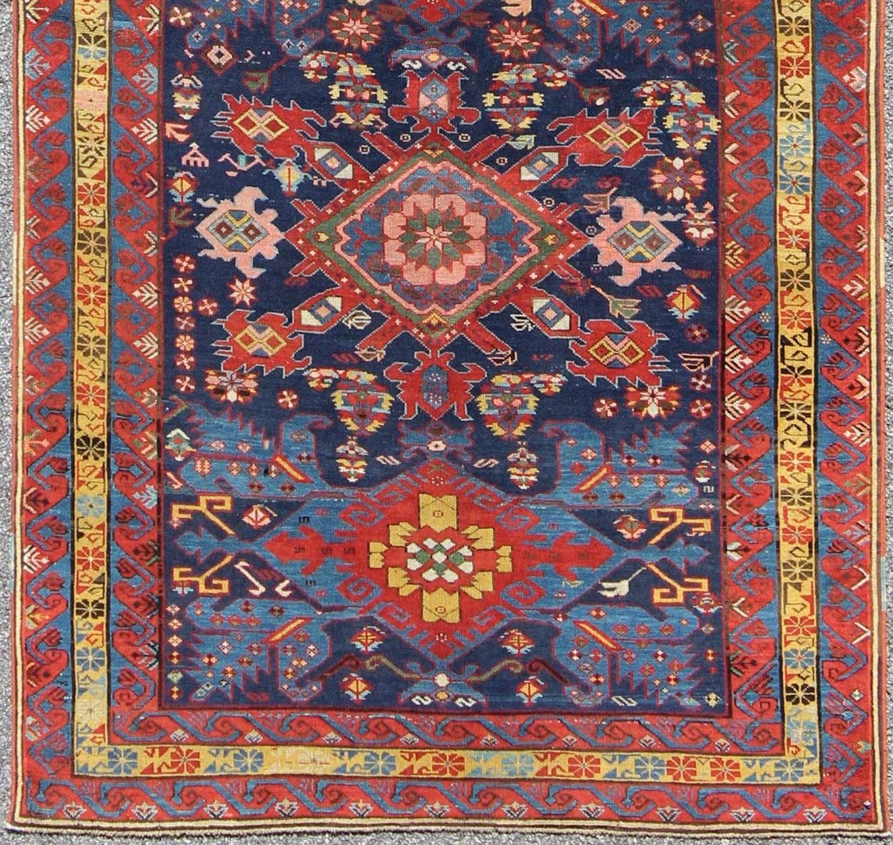 This elegant 19th Century Seychour rug originates from the mountainous region of the Caucuses. A beautiful row of five diamond-shaped medallions run the entire length of the rug, which incorporates various rich hues of blues, reds and
